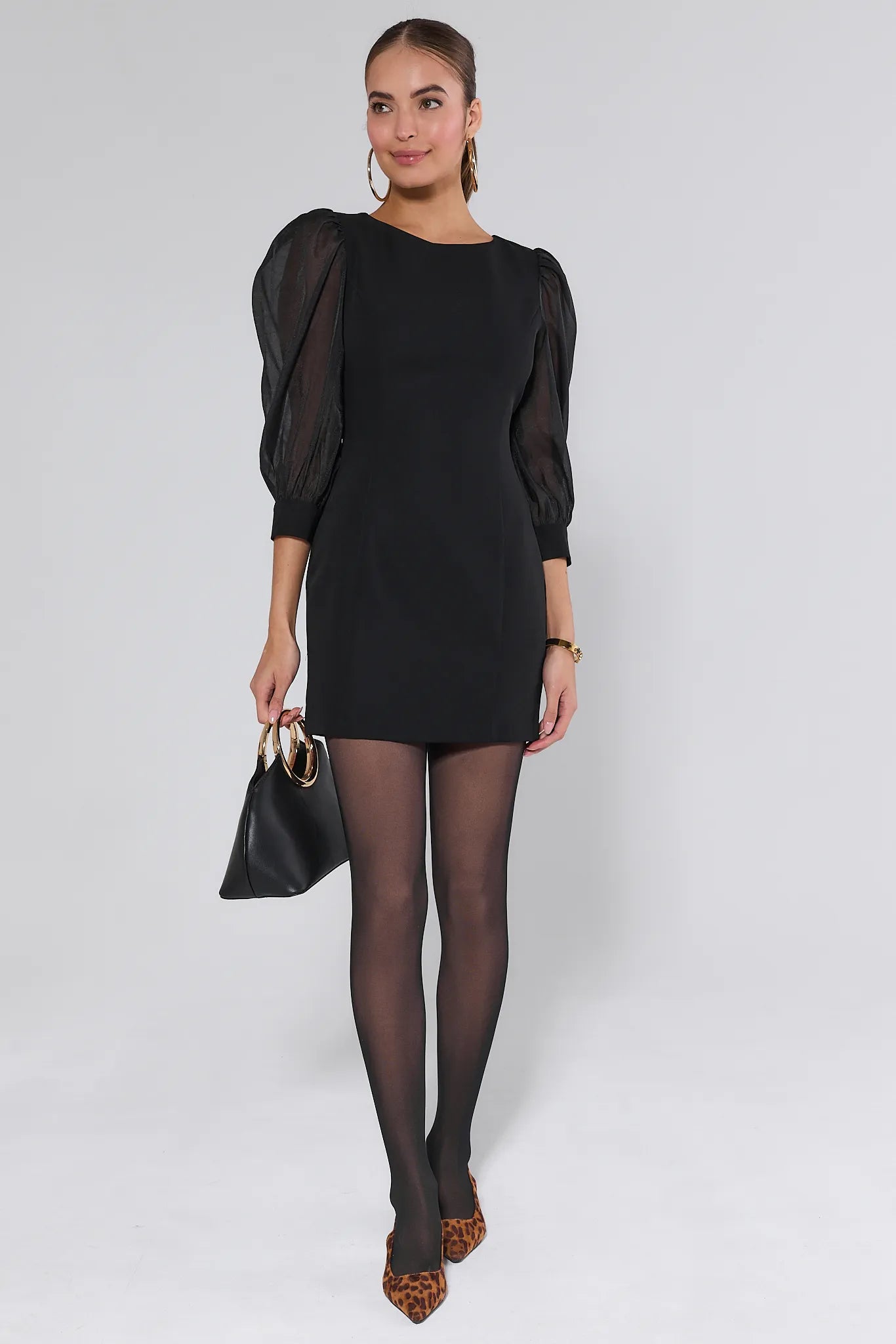 Woman wearing a black Veronica Dress with sheer sleeves against a plain background