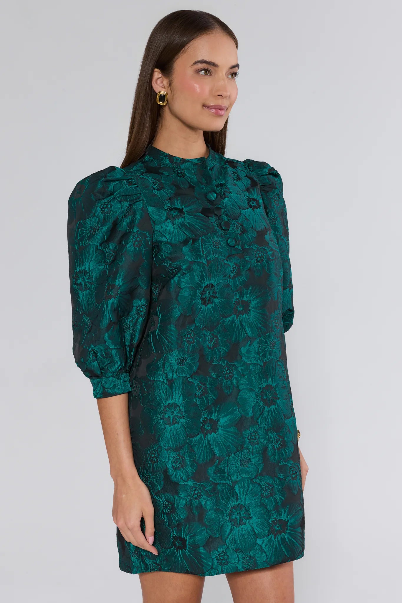 Woman wearing a green floral dress against a white background