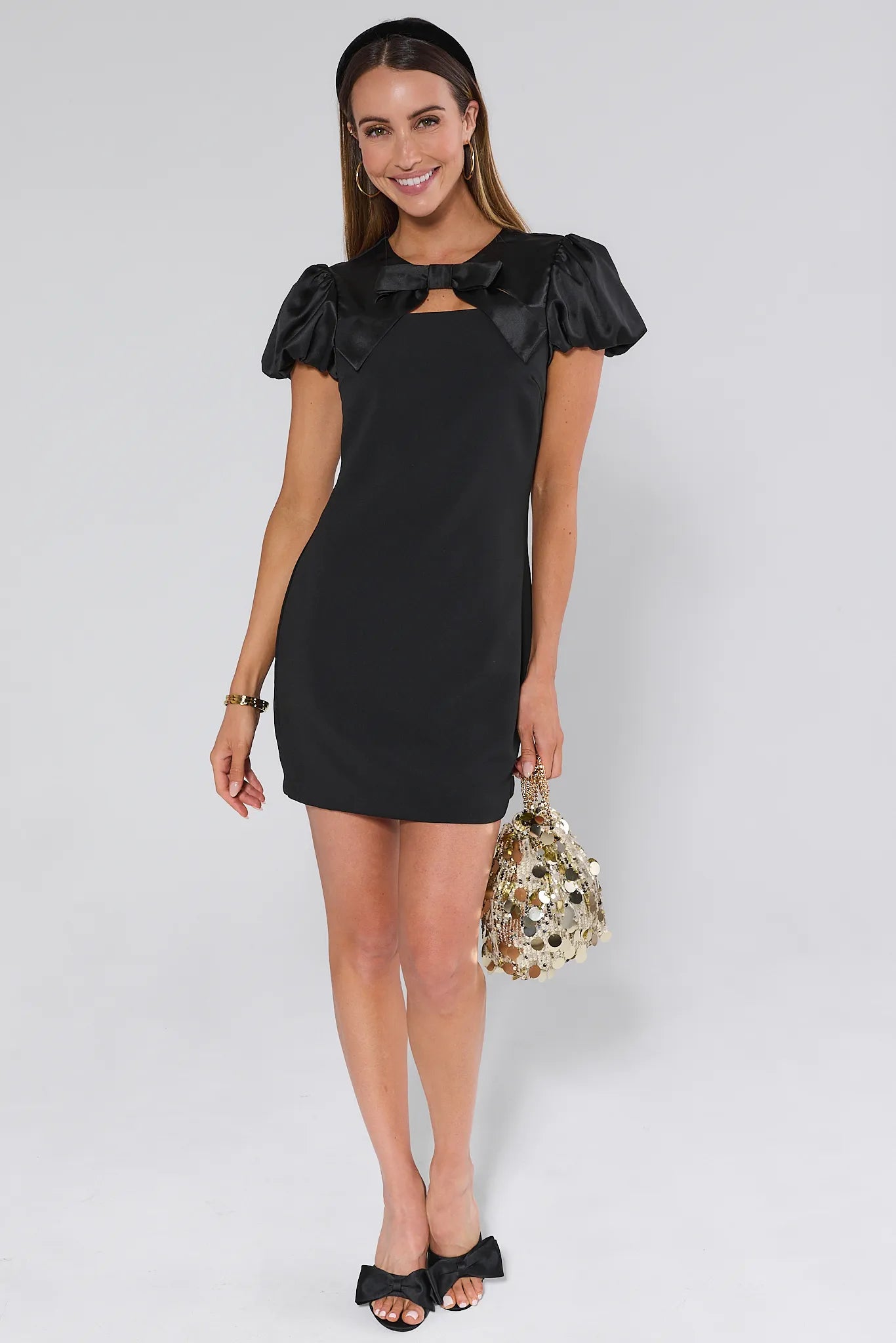 Black Anna dress with ruffled sleeves and a bow detail on a plain background