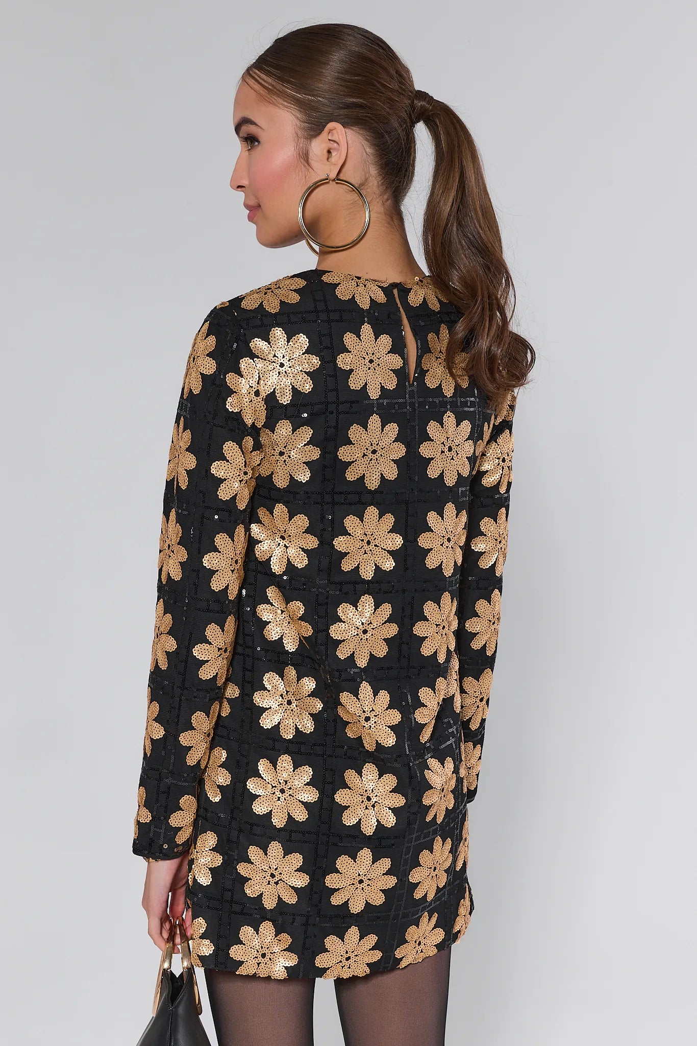 Woman wearing a Claudia Sequin Floral Mini Dress on a white background