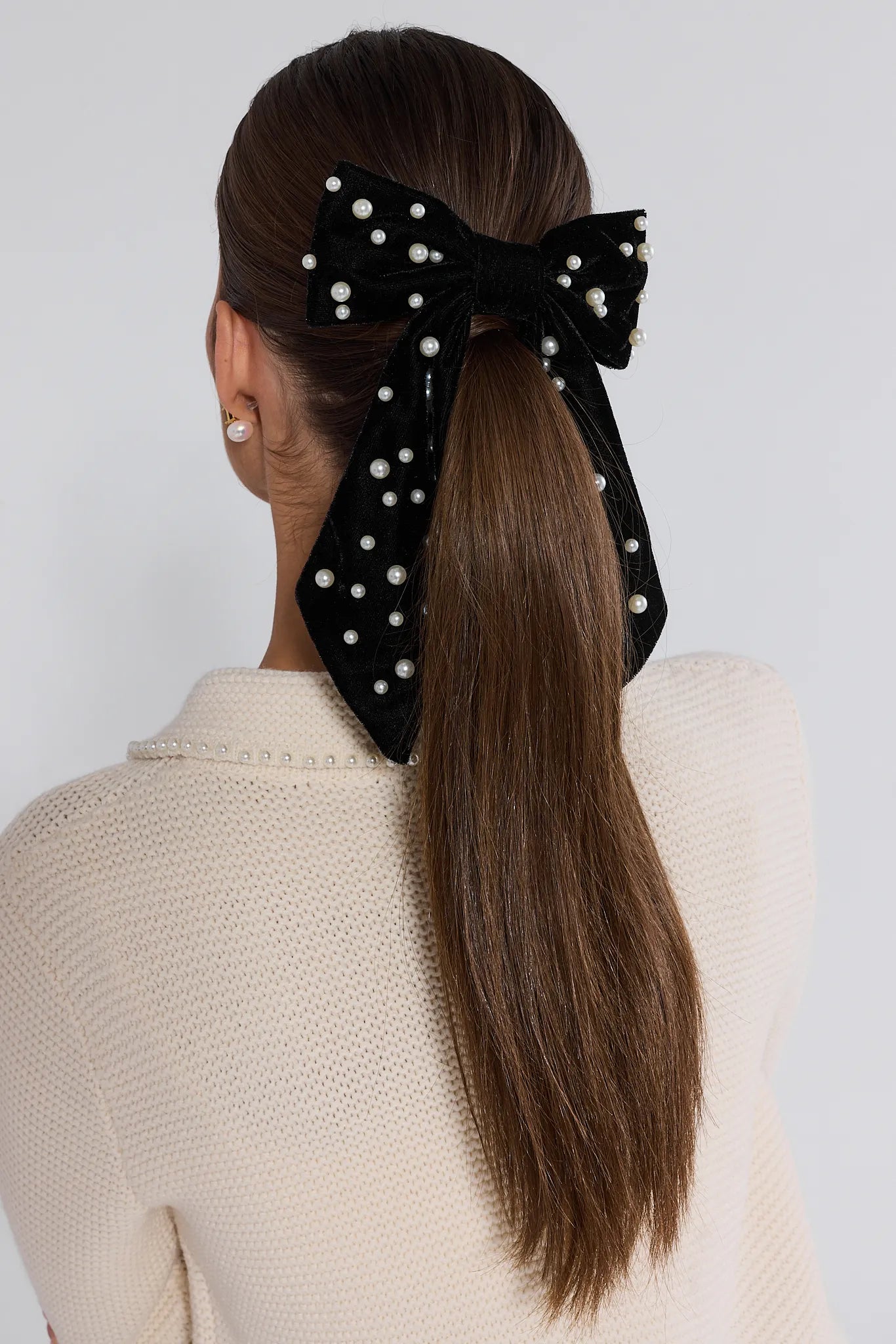Person with a Mallory Black Pearl Bow in their hair against a white background