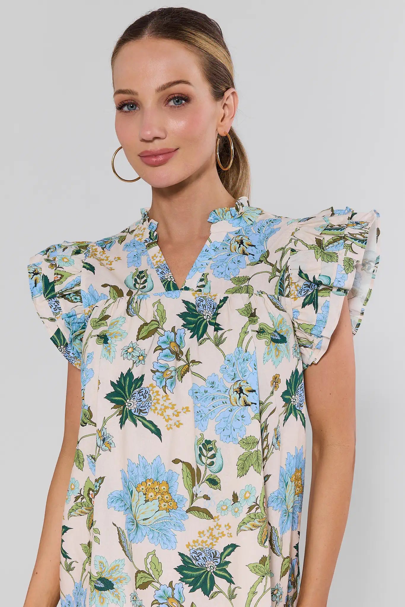 Woman wearing a floral dress with blue flowers on a plain background