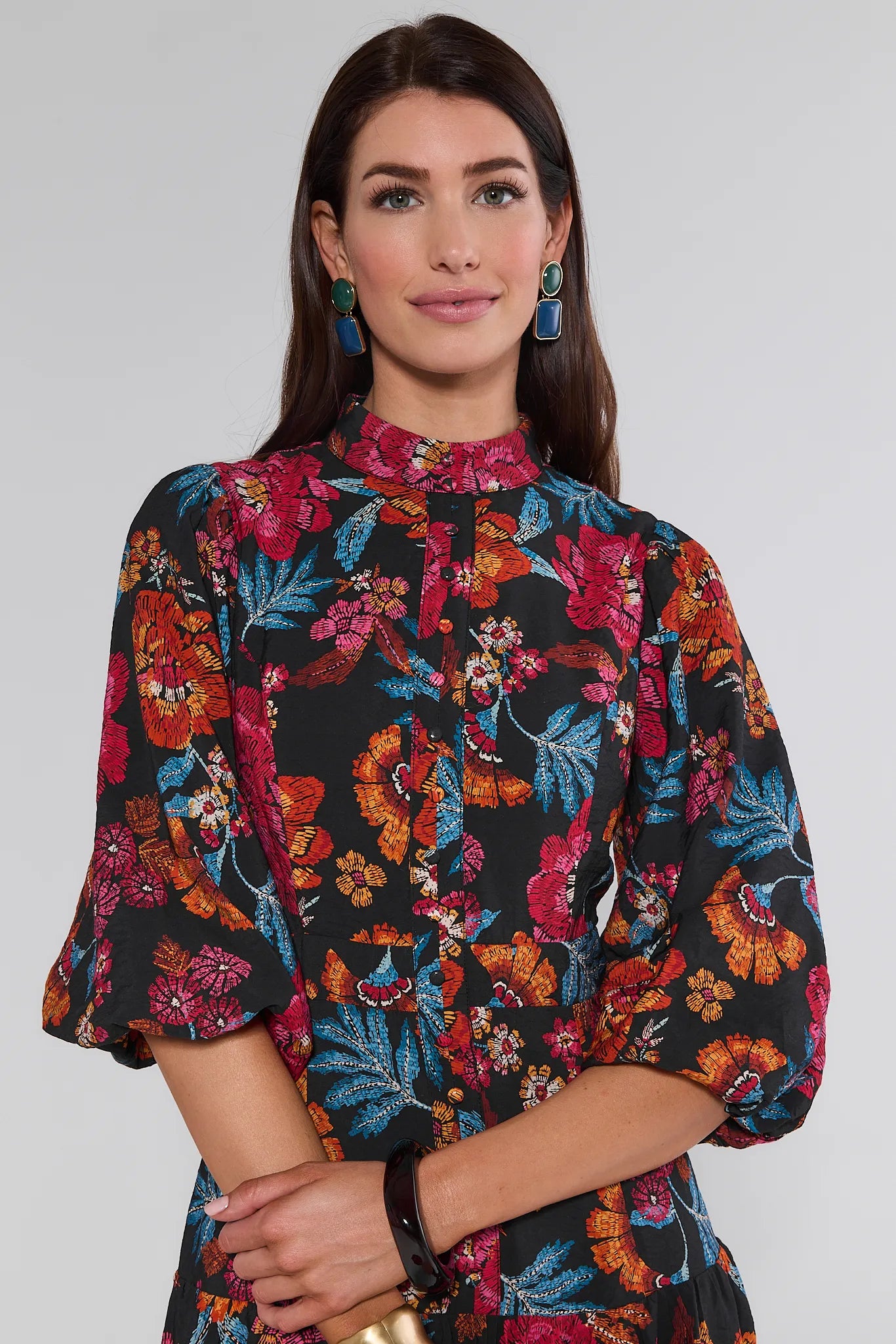 Woman wearing a colorful floral Desi Dress against a plain background