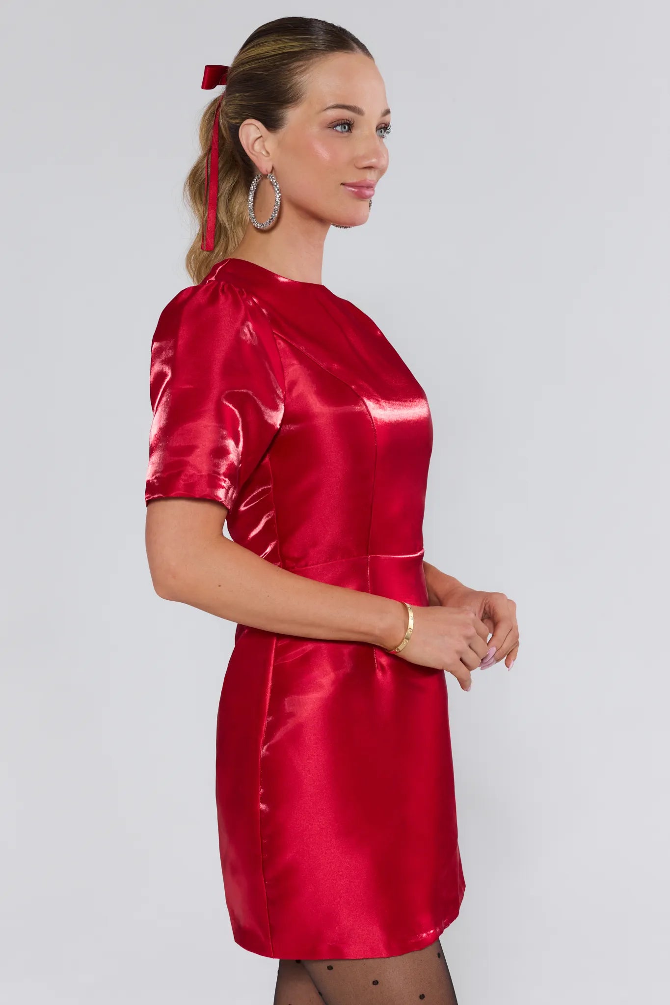 Woman wearing a red satin dress against a plain background