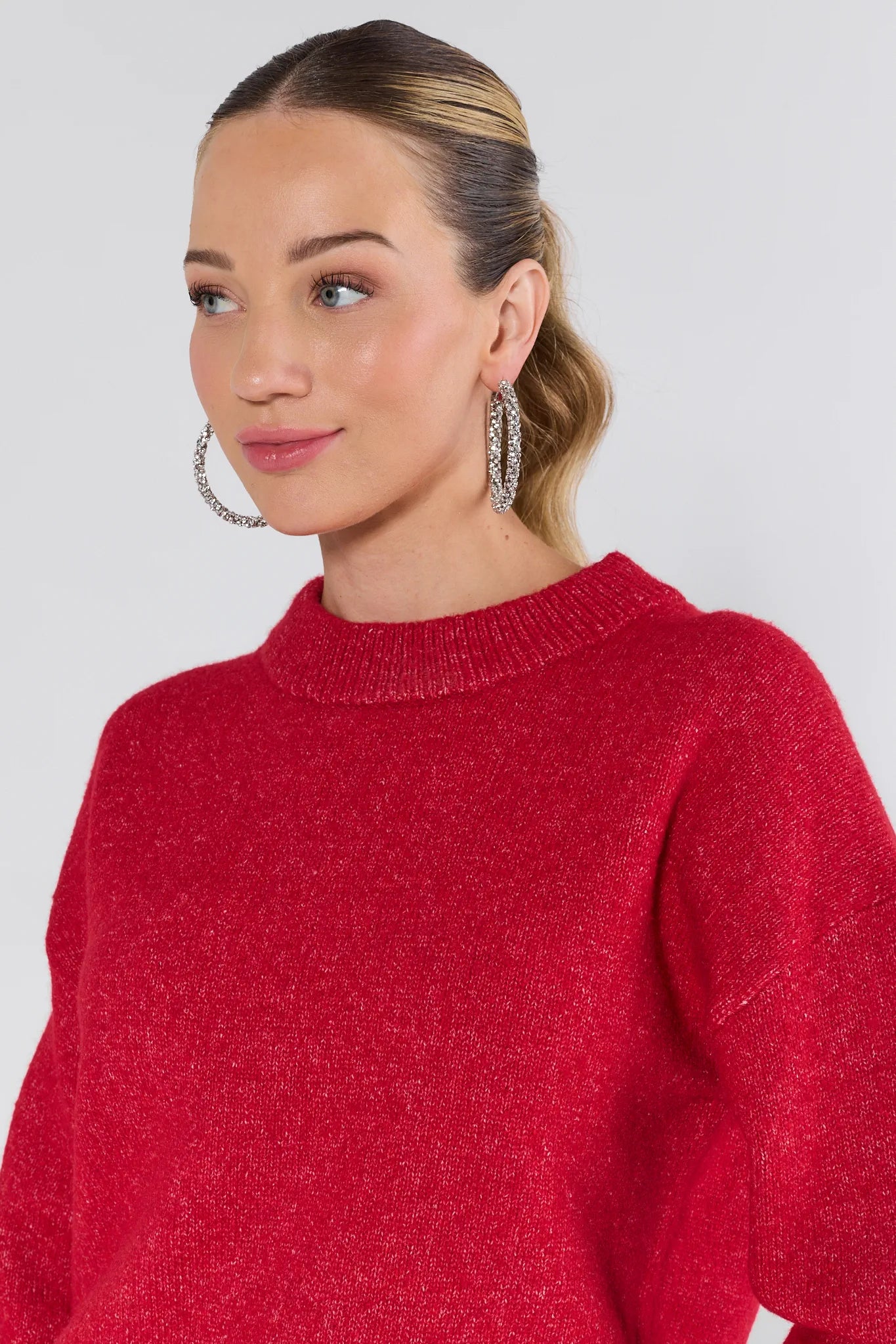 Woman wearing a red sweater against a plain background