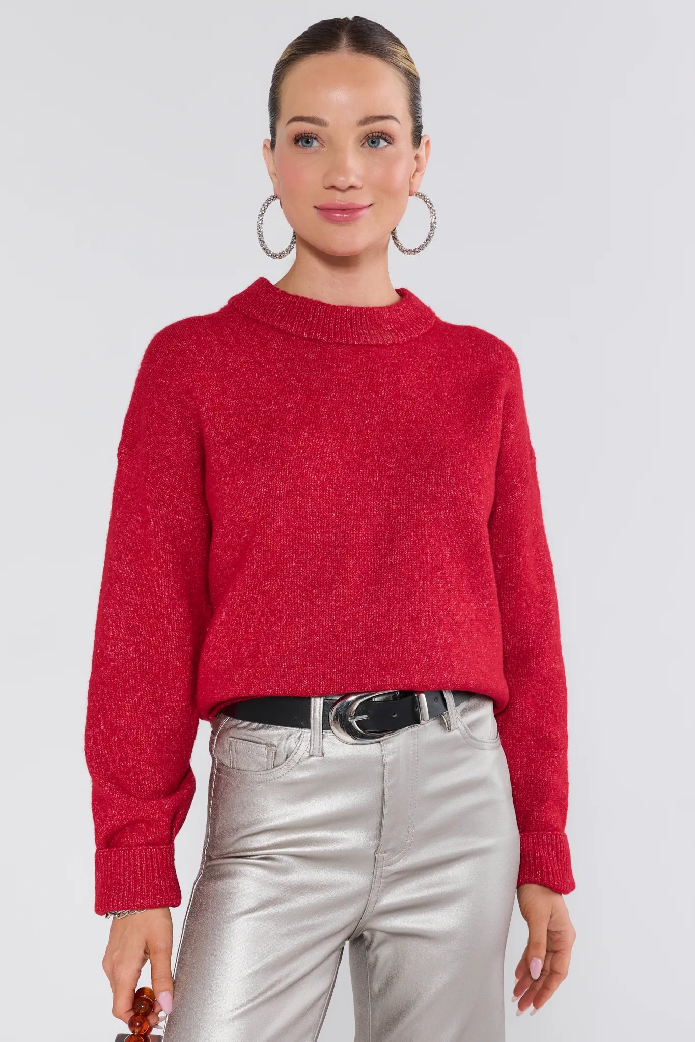Person wearing a red sweater and silver pants on a white background