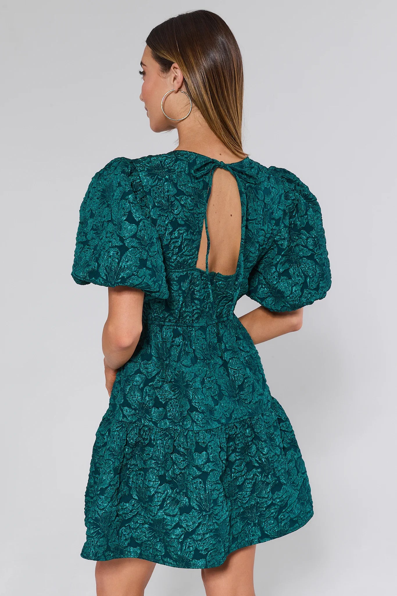 Woman wearing a teal floral dress with puff sleeves on a white background