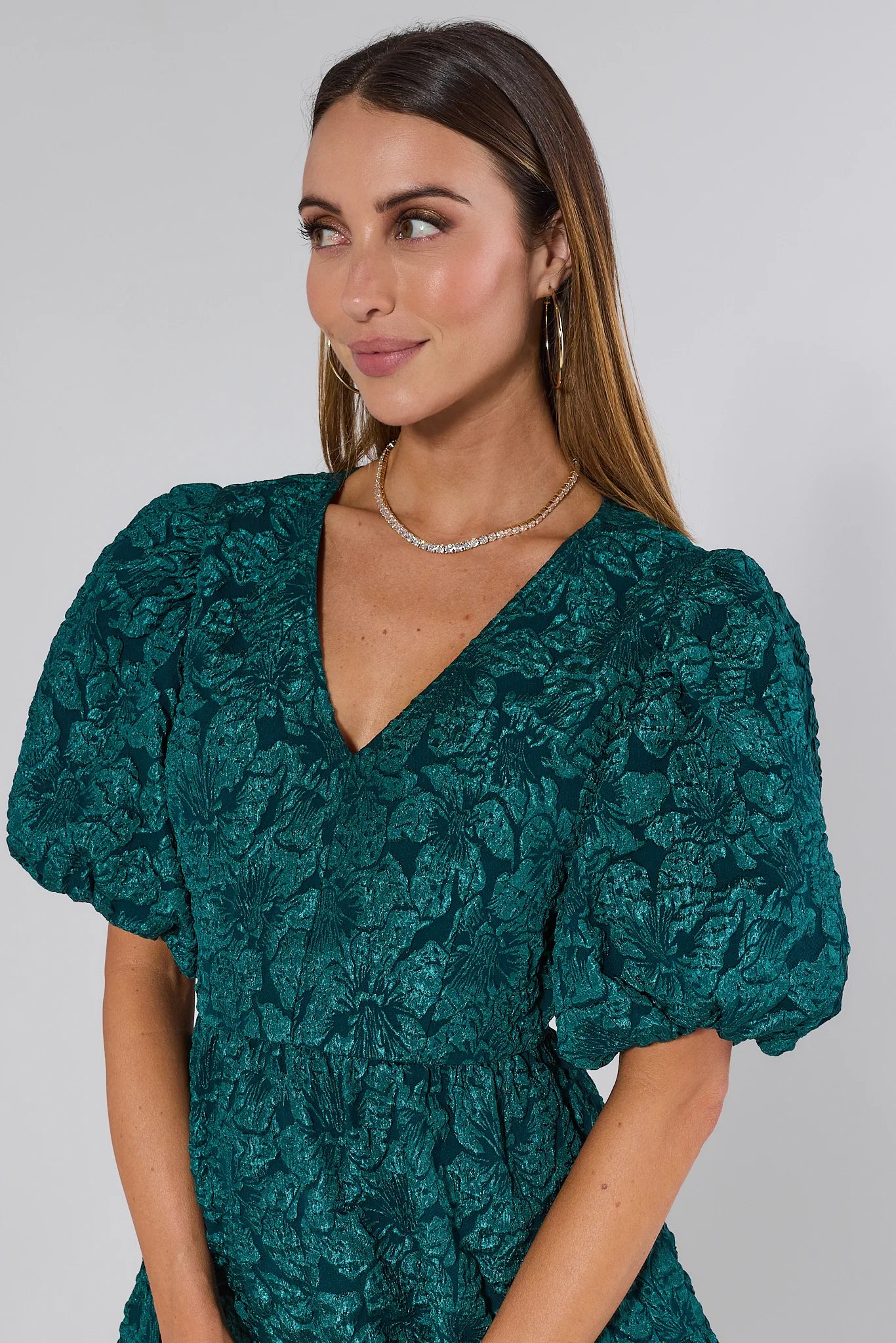 Woman wearing a green floral dress with puff sleeves against a plain background