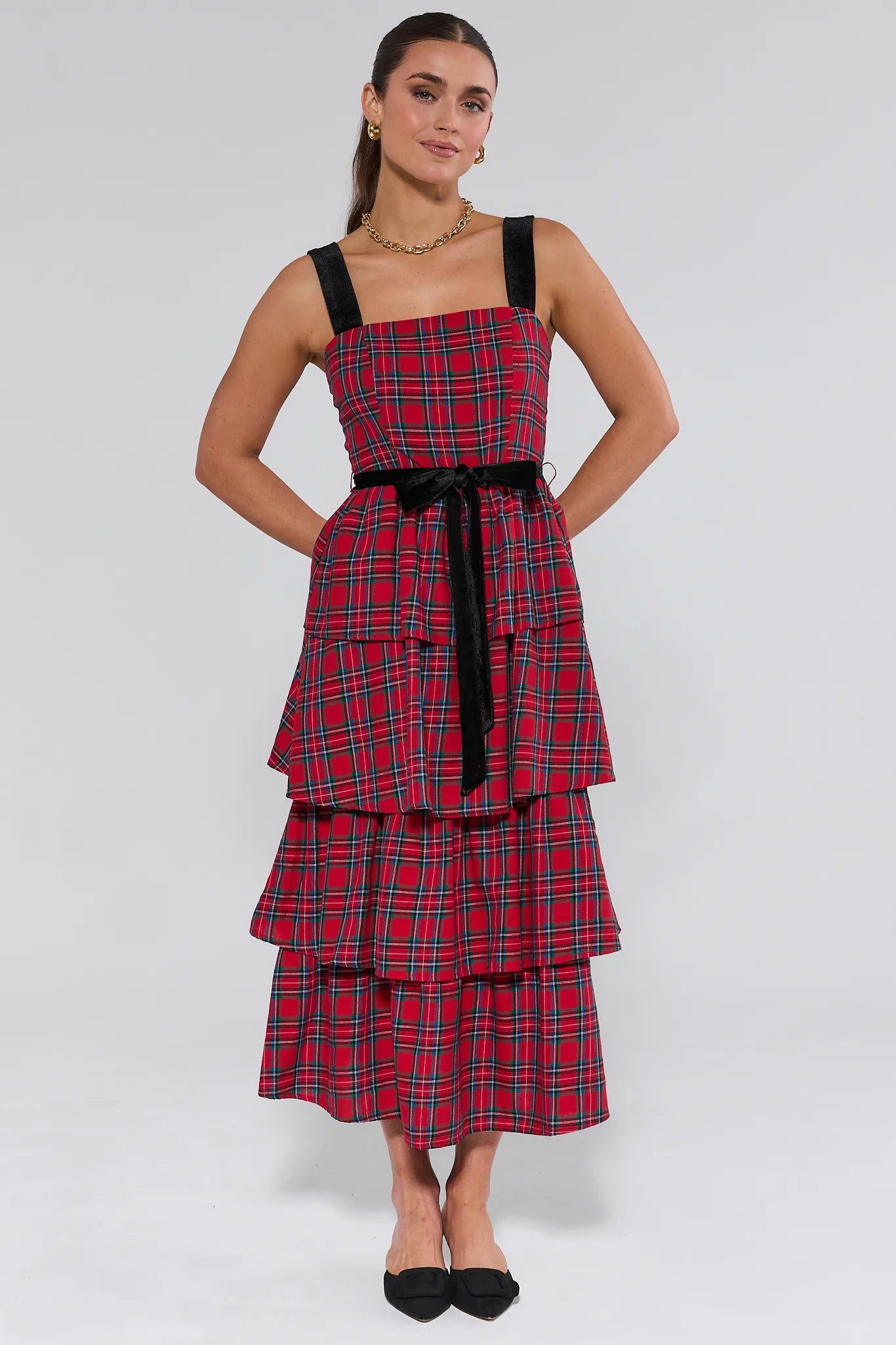 Woman wearing a red plaid catalina dress with black straps on a white background
