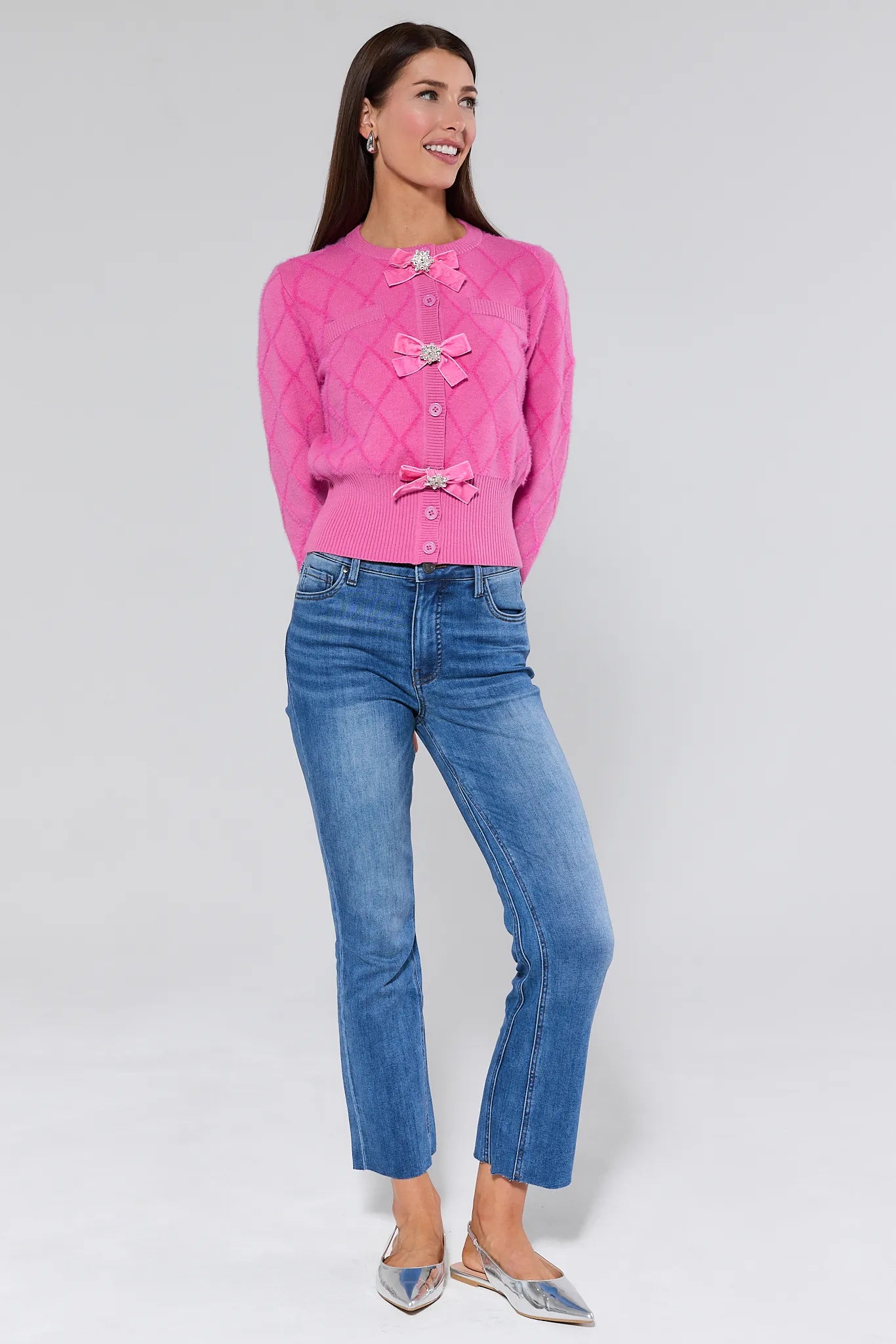 Woman wearing a Emily Pink Bow Cardigan with decorative bows and buttons on a plain background