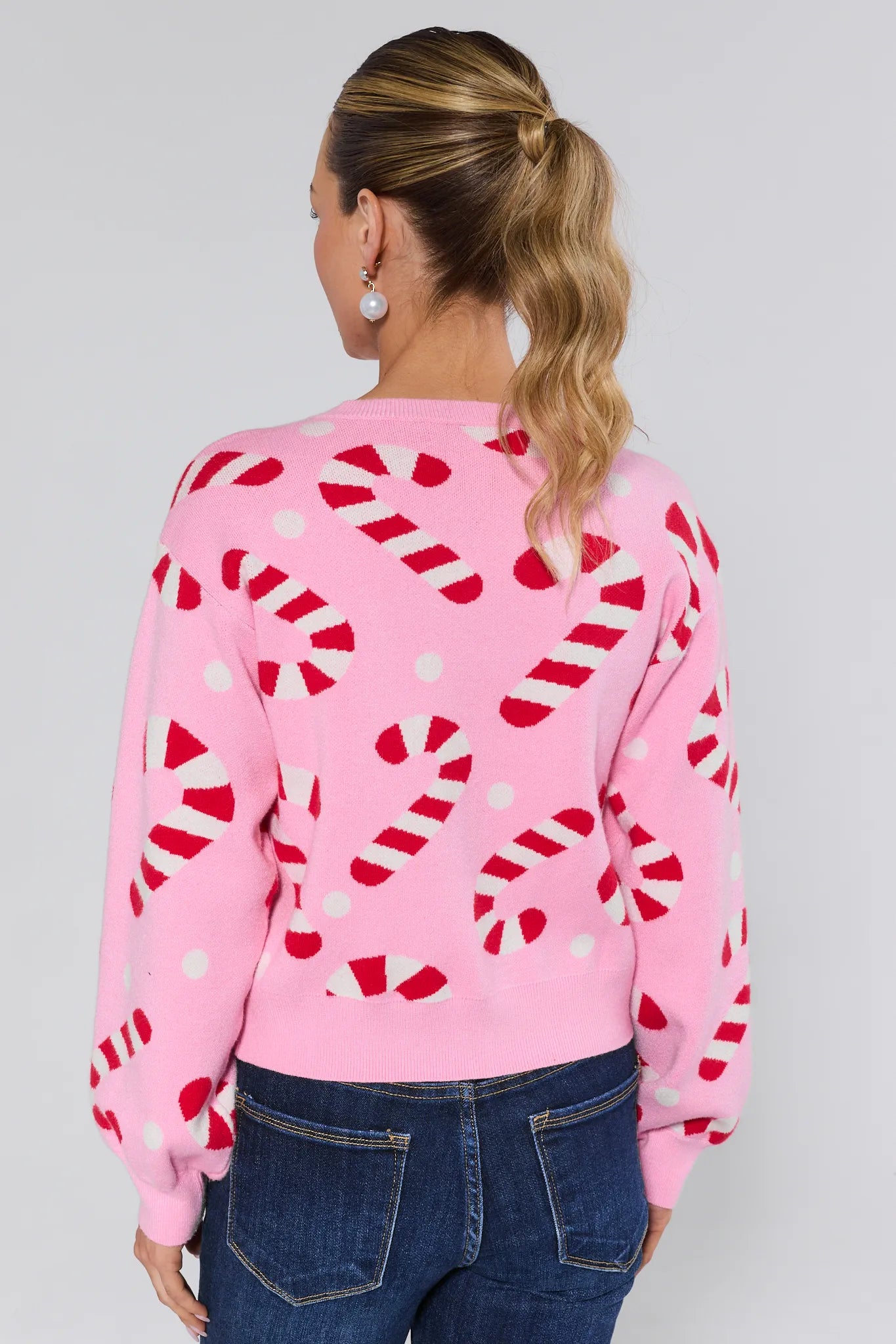 Woman wearing a Hollis Pink Candy Cane Sweater on a plain background