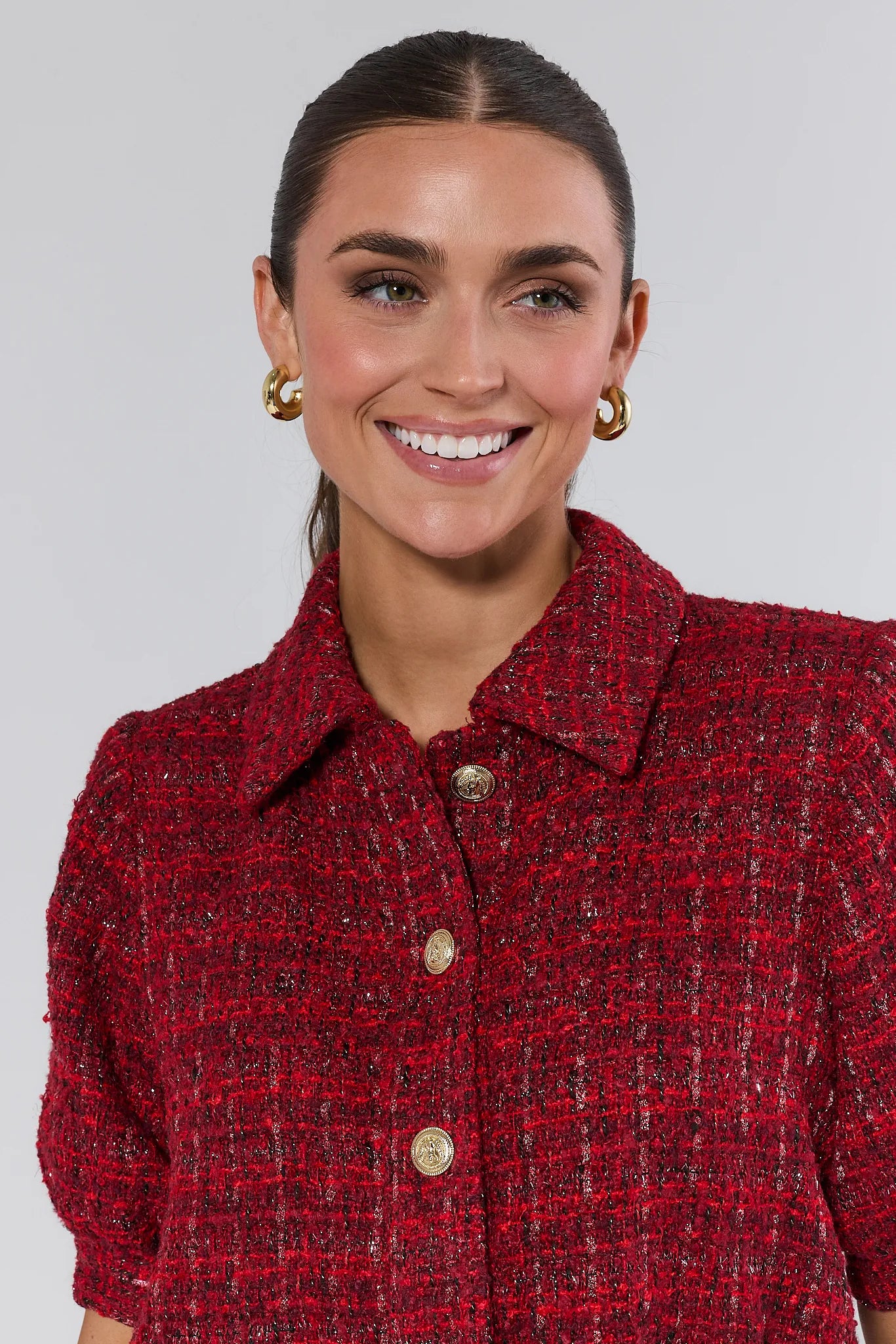 Woman wearing a red tweed jacket with a plain background