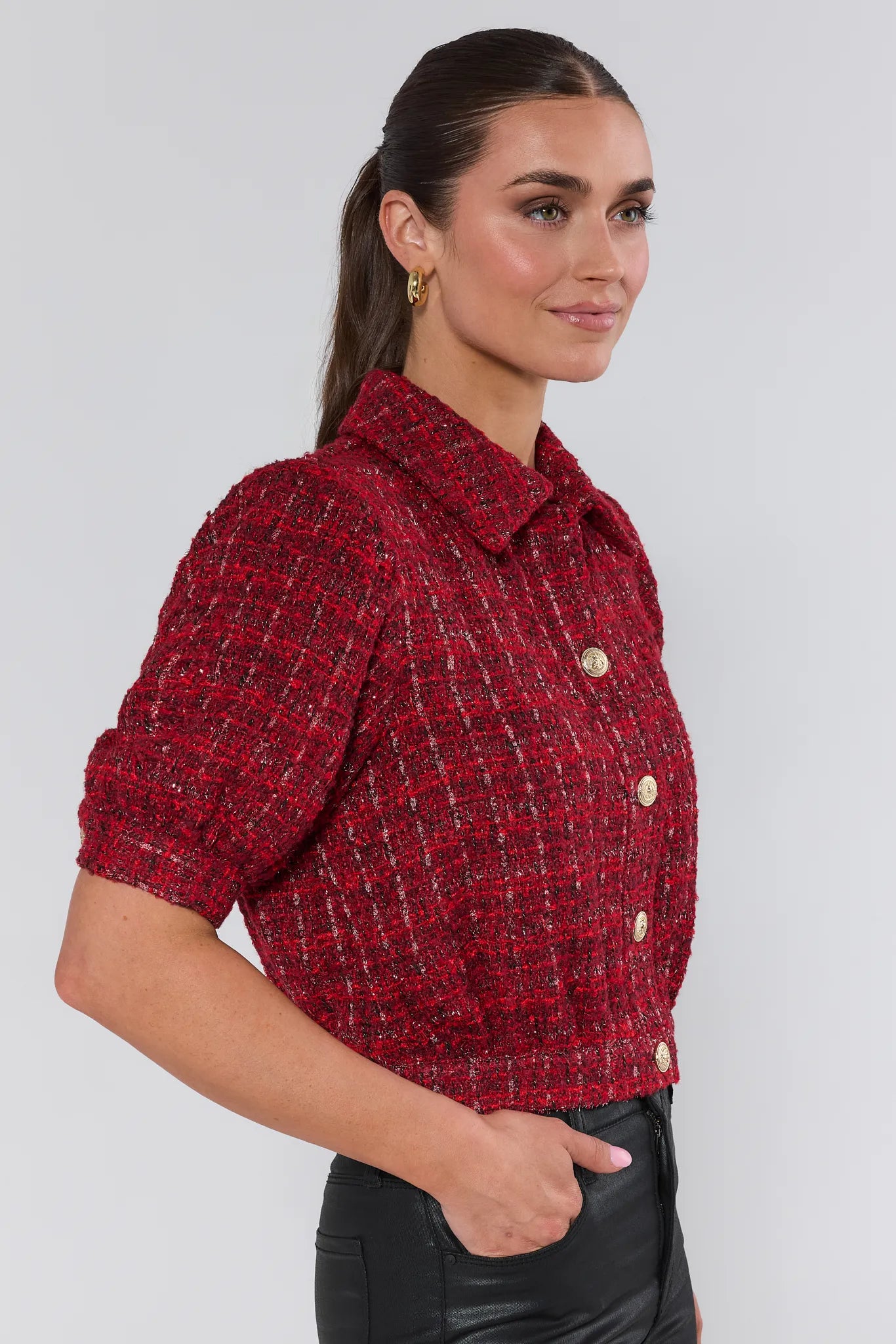 Woman wearing a red checkered blouse with short sleeves against a white background
