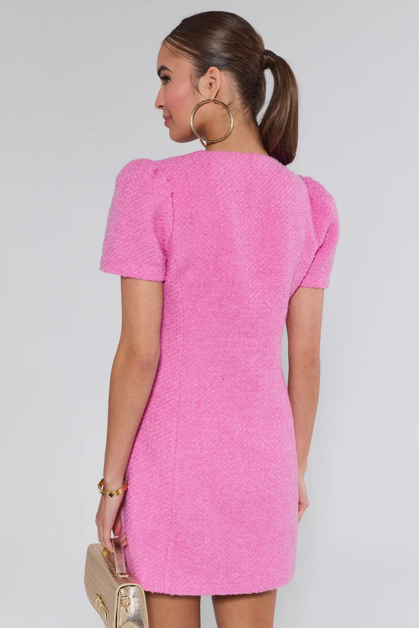 Woman wearing a pink missy dress with buttons on a white background