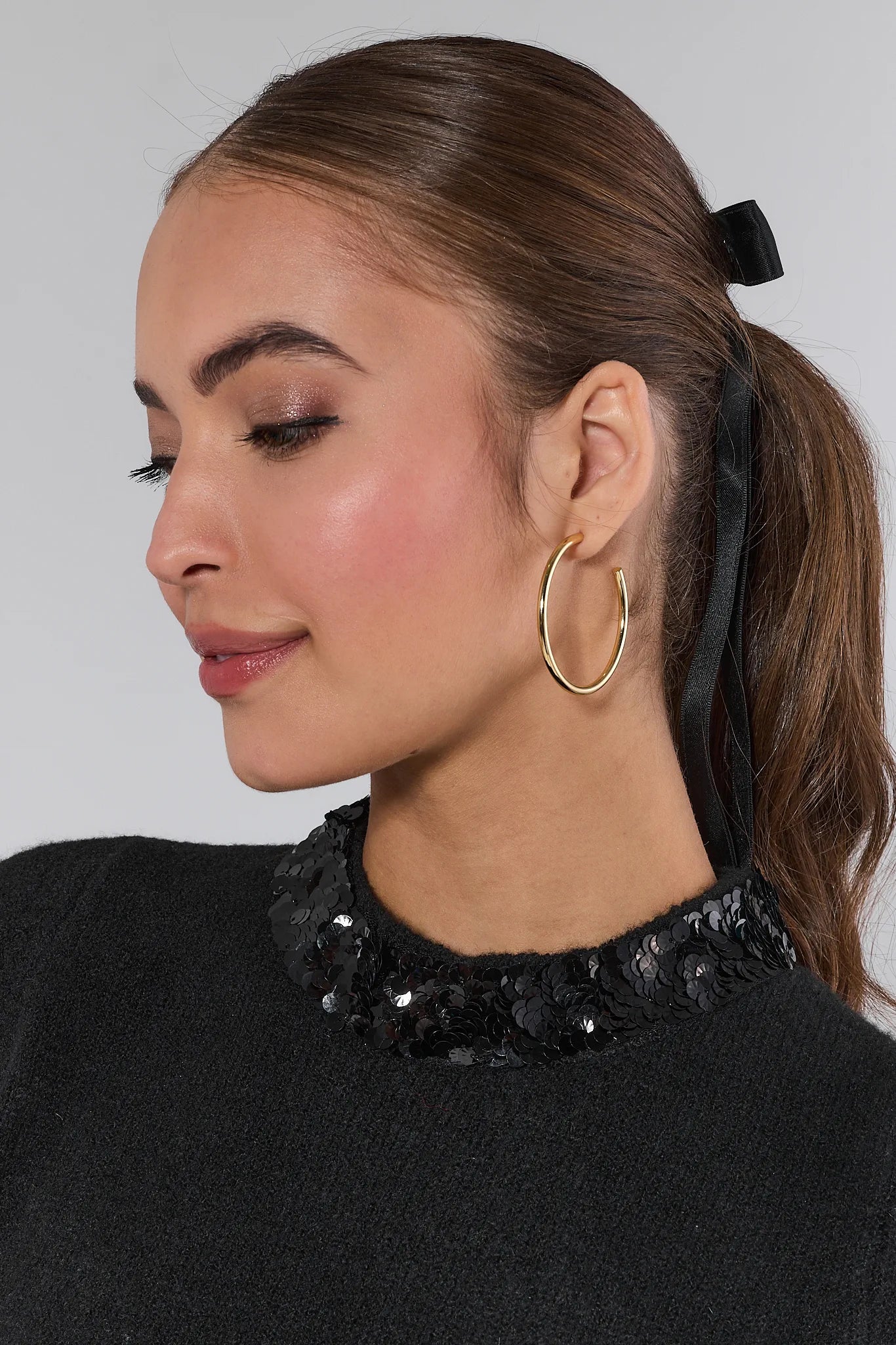 Woman wearing a black short-sleeve Vicki Sweater with a sequin collar against a white background