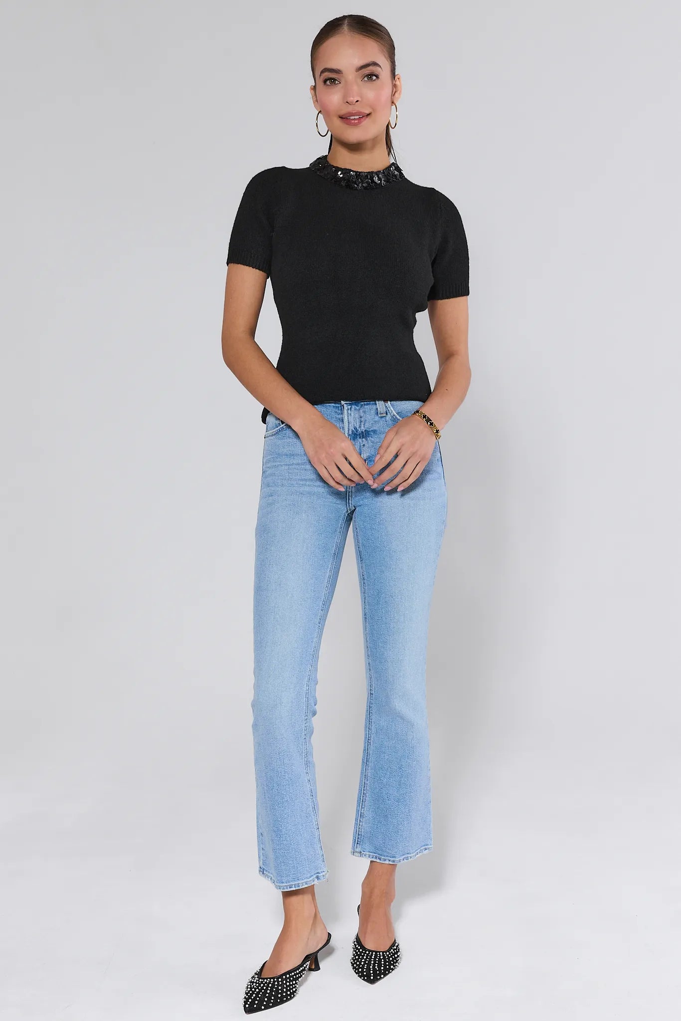 Woman wearing a black short-sleeve Vicki Sweater with a sequin collar against a white background