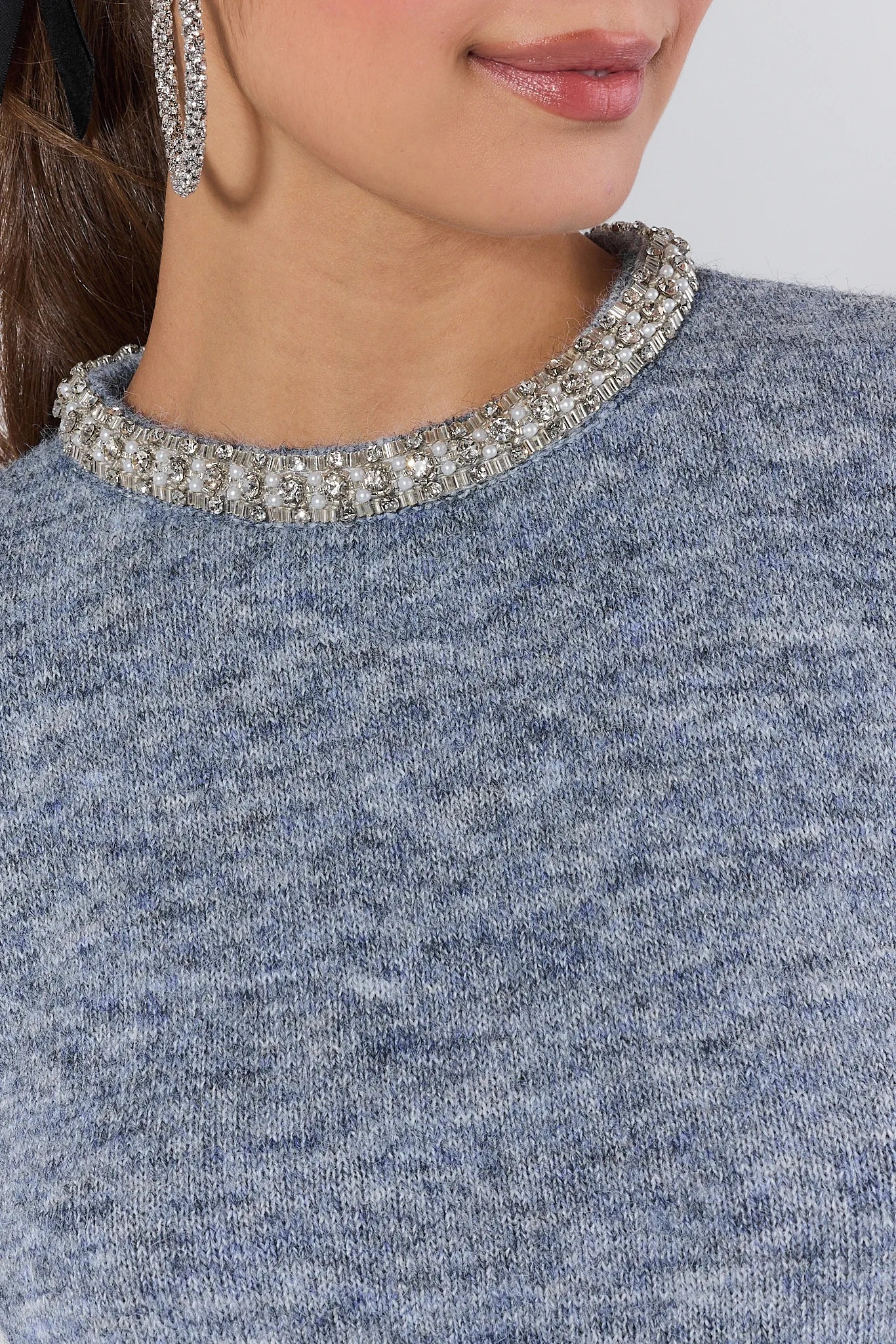 Woman wearing a Blythe sweater with a decorative neckline against a plain background