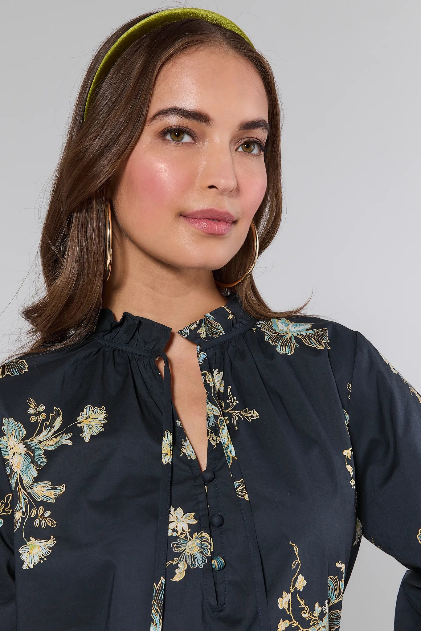 Woman wearing a dark blue Michelle Top with floral embroidery on a plain background