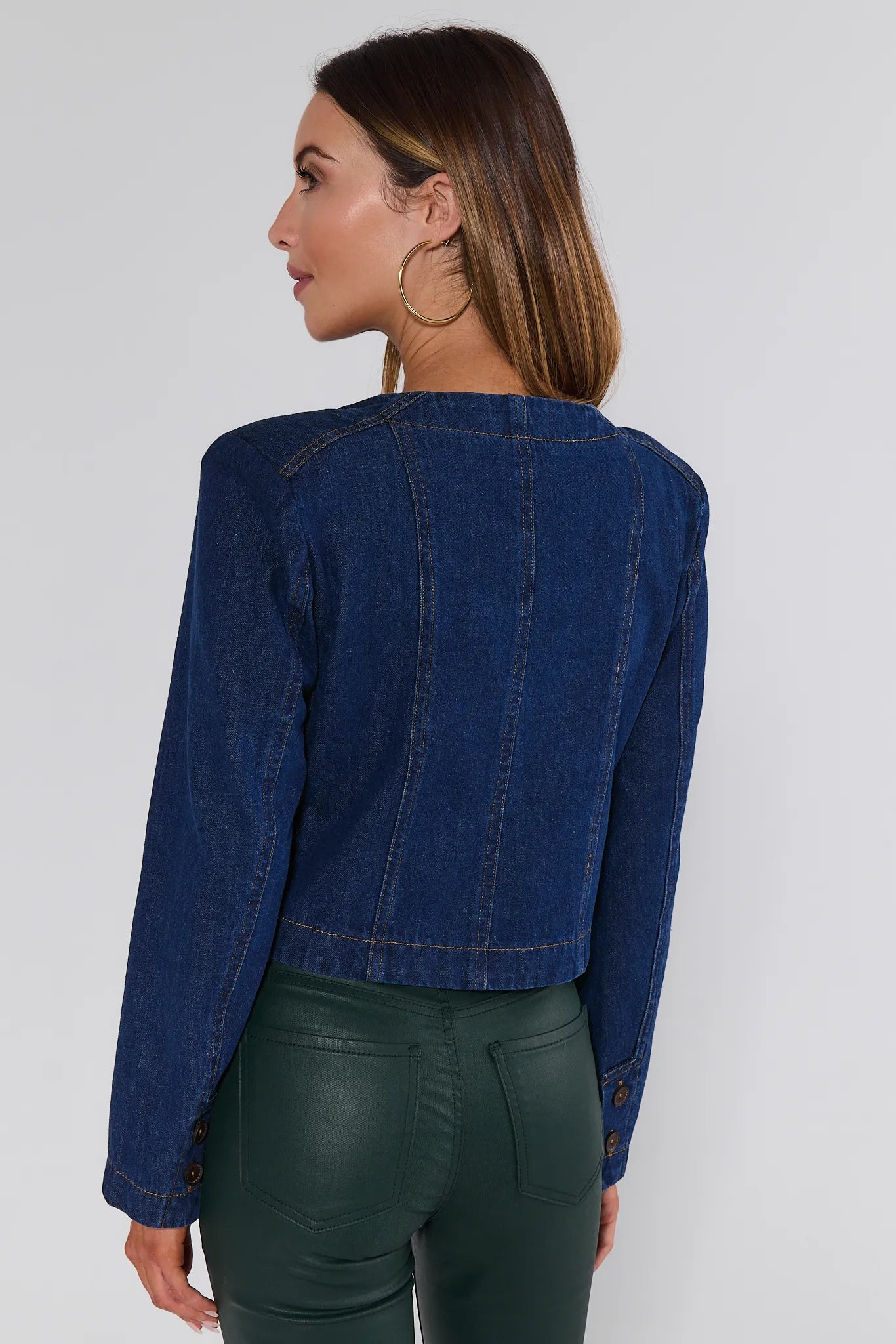 Woman wearing a blue denim Vera Jacket and green pants on a white background