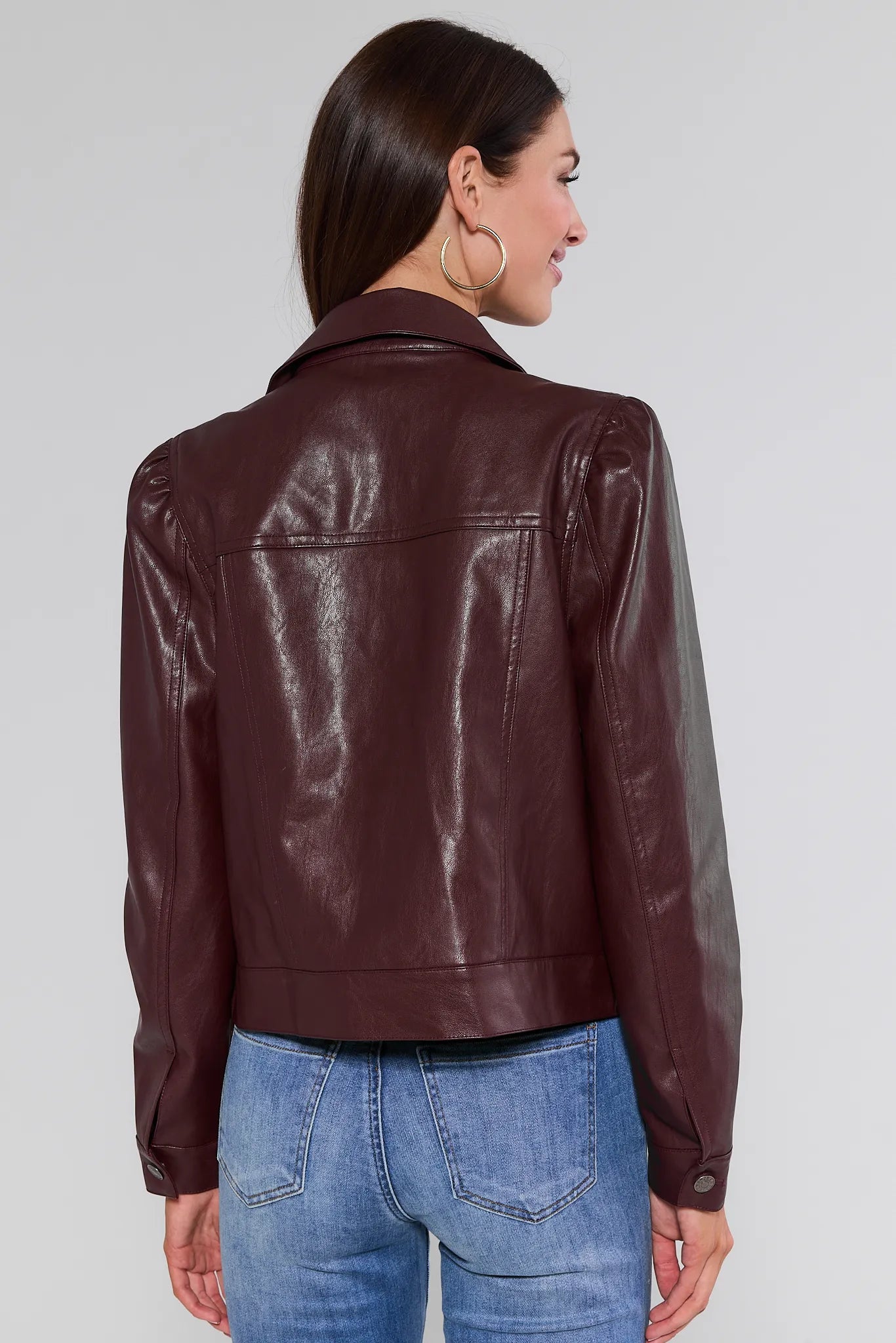 Woman wearing a brown Roxanna Leather Jacket and blue jeans on a white background
