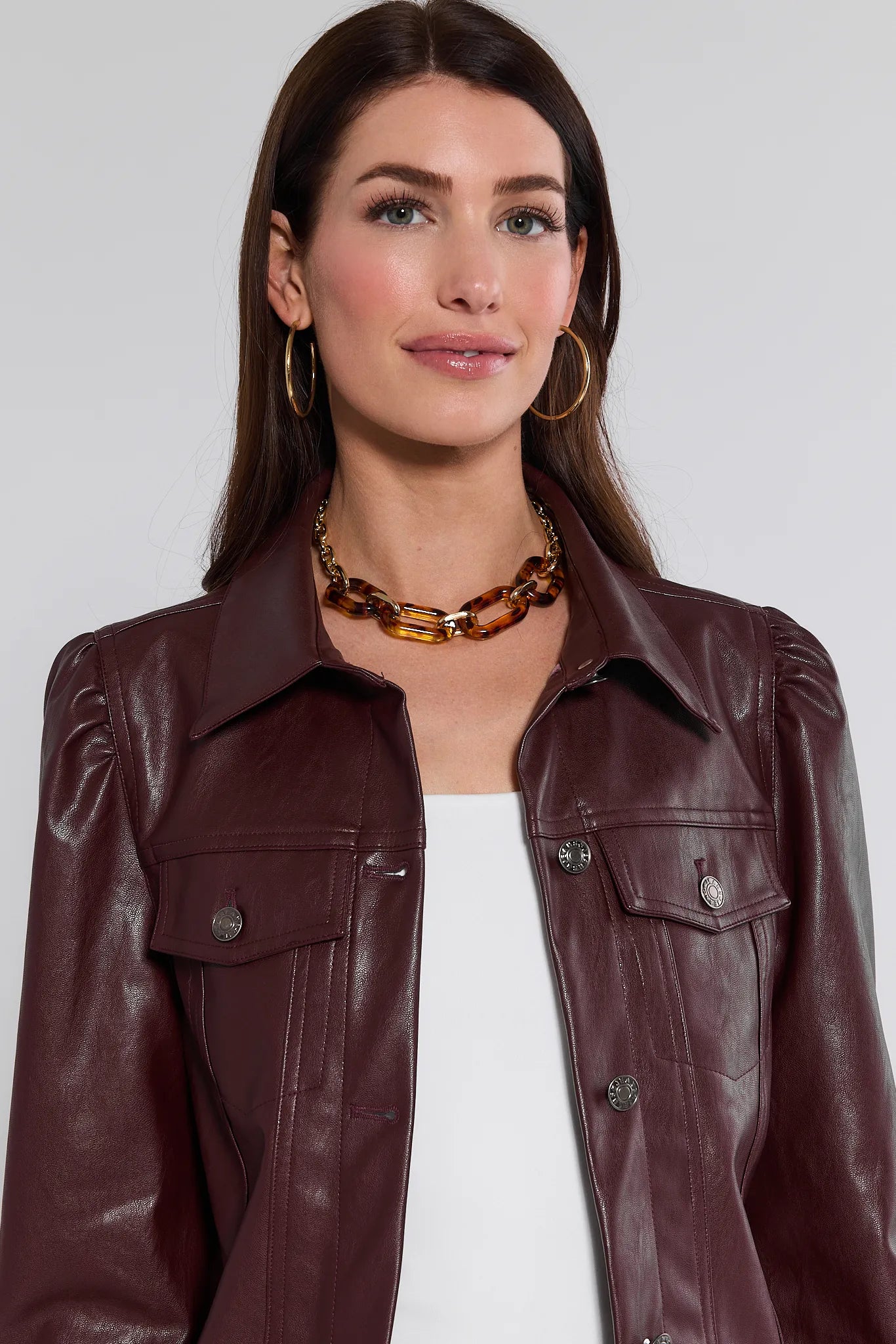 Woman wearing a brown Roxanna Leather Jacket with a plain background