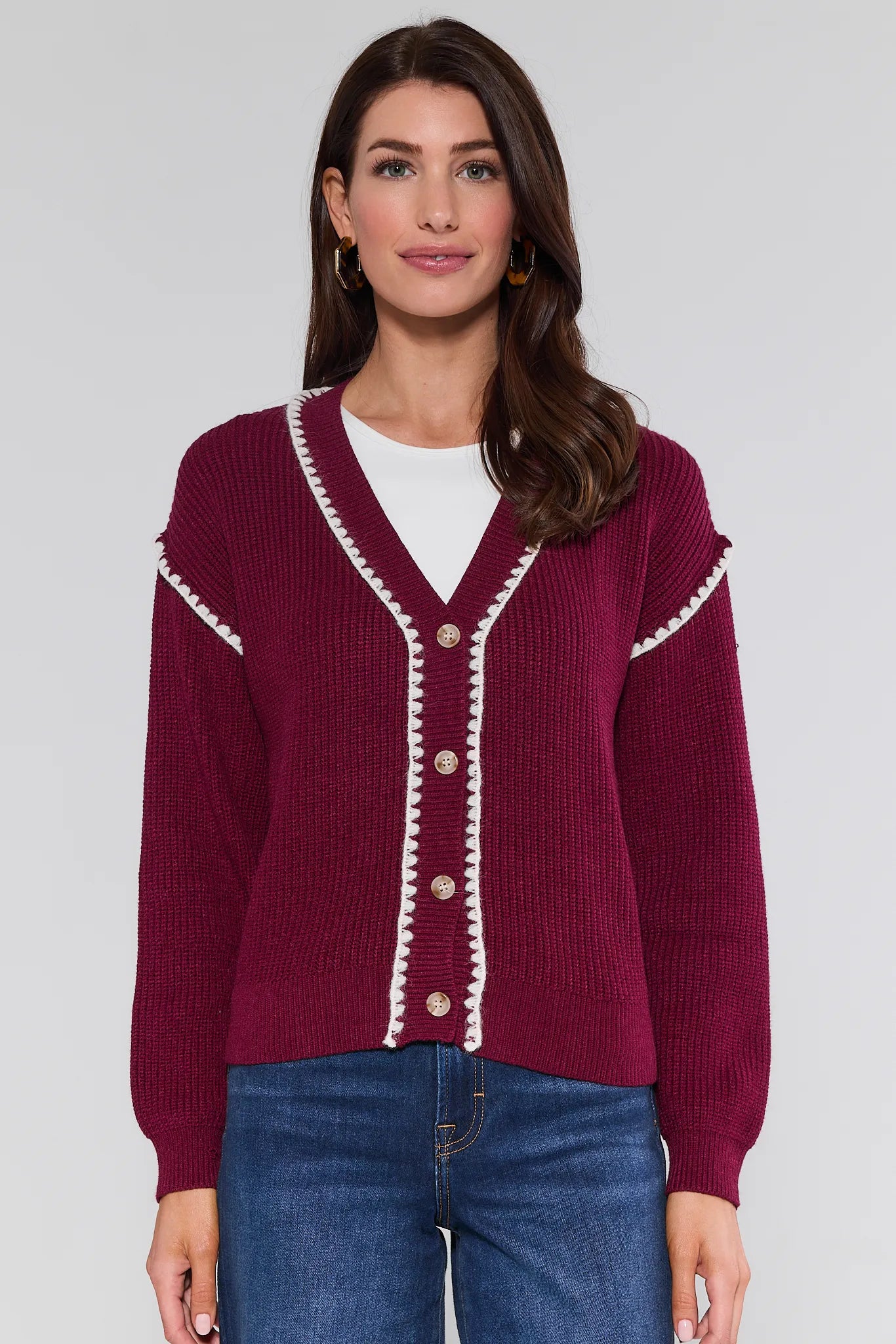 Woman wearing a burgundy Morgan Cardigan with white trim on a plain background