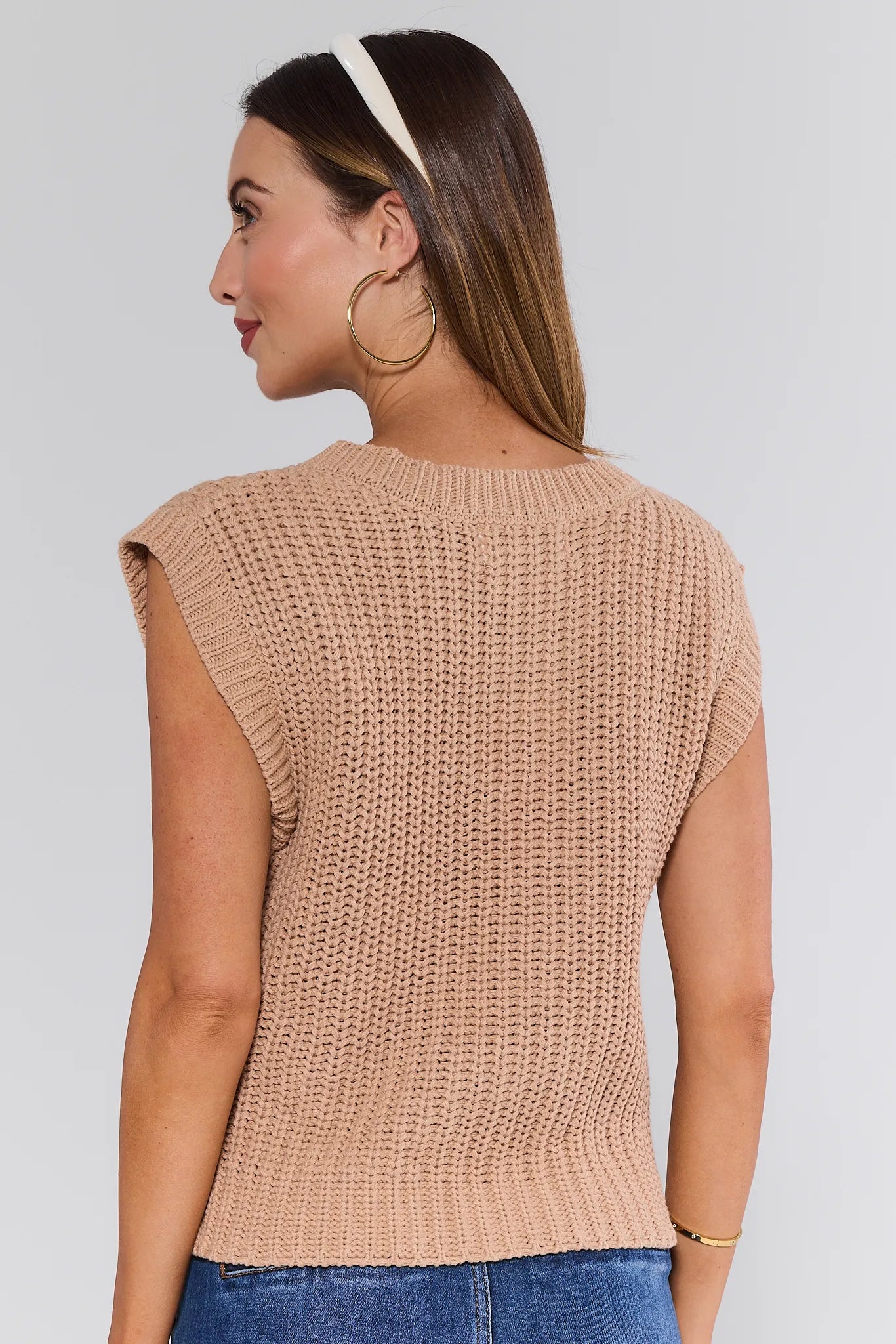 Woman wearing a beige knitted sleeveless Angelina Vest against a plain background