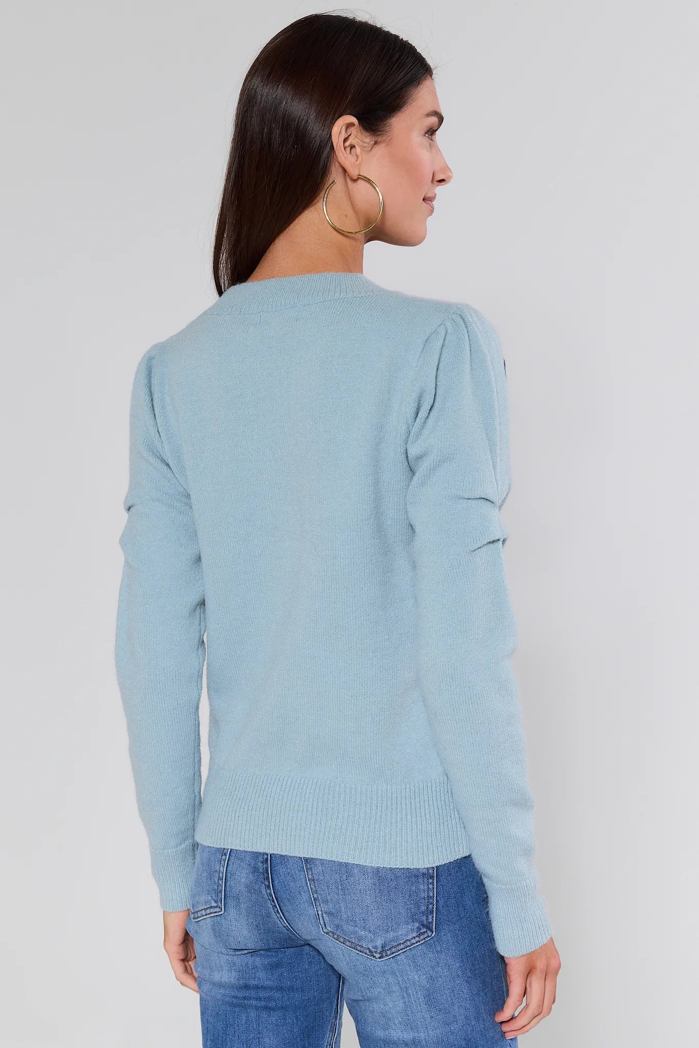 Woman wearing a Natasha Blue Embroidered Sweater with black embroidery on a plain background