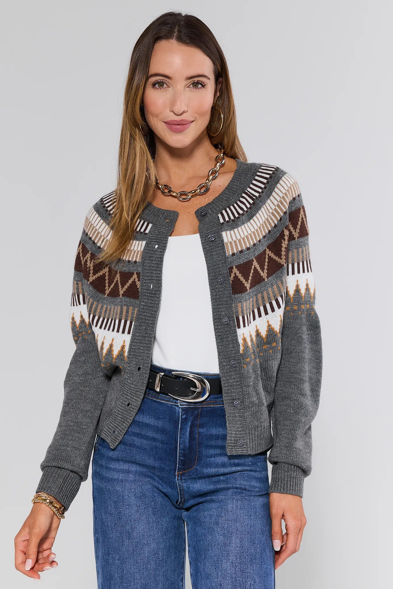 Woman wearing a patterned Alyssa Cardigan over a white shirt and blue jeans on a plain background