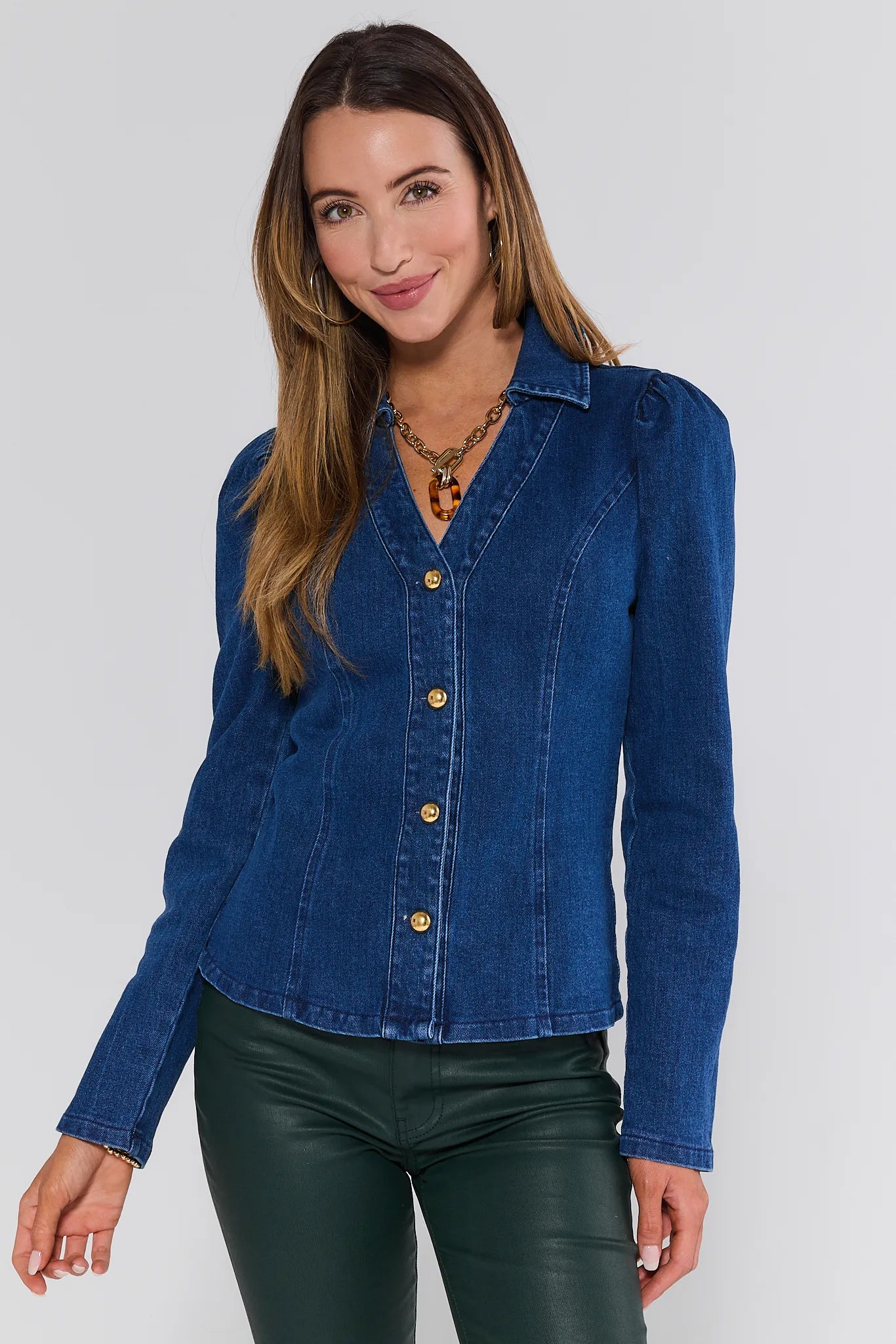 Woman wearing a blue denim Nellie Top with a plain background