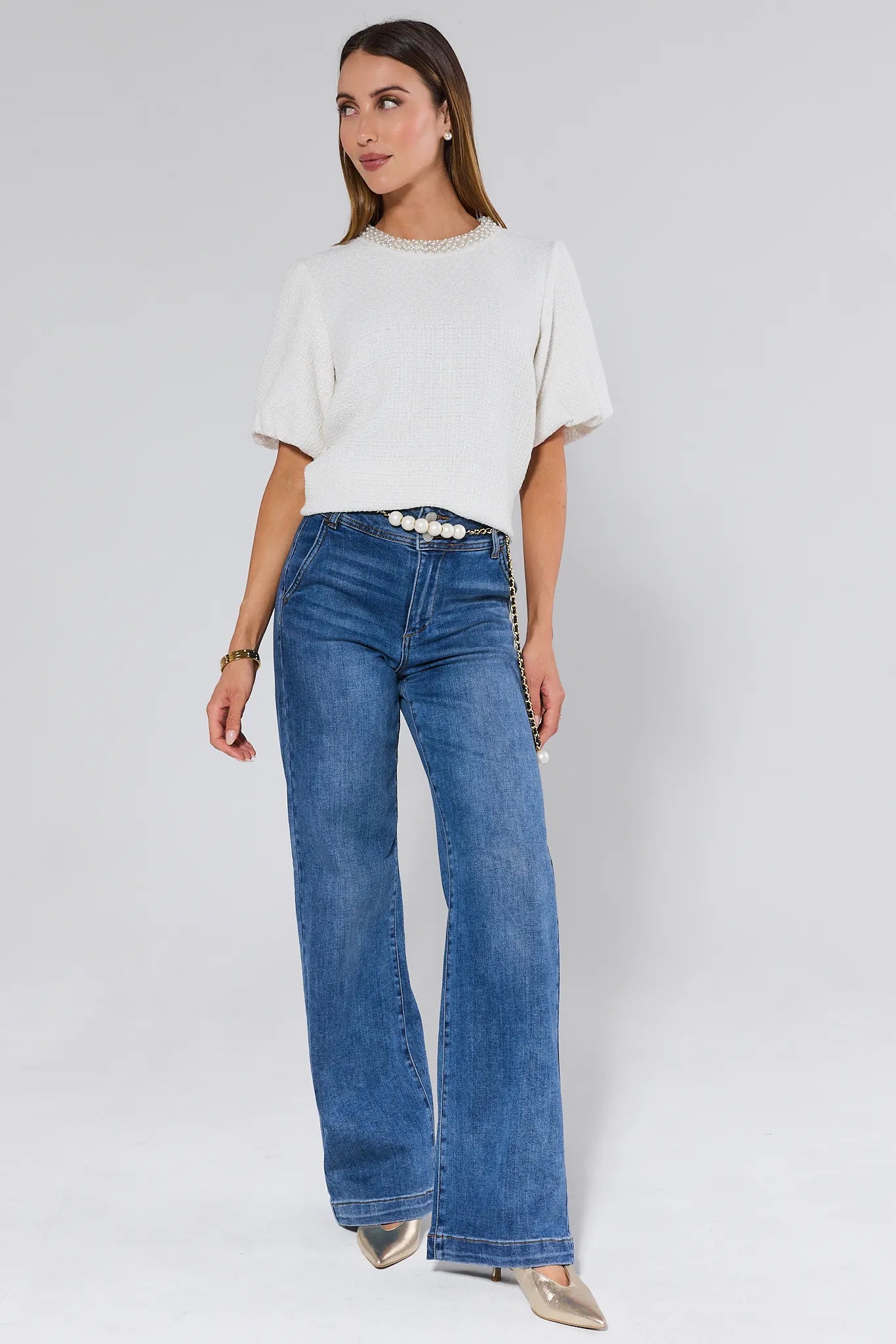 Woman wearing a white Blakely Top with pearl details against a plain 