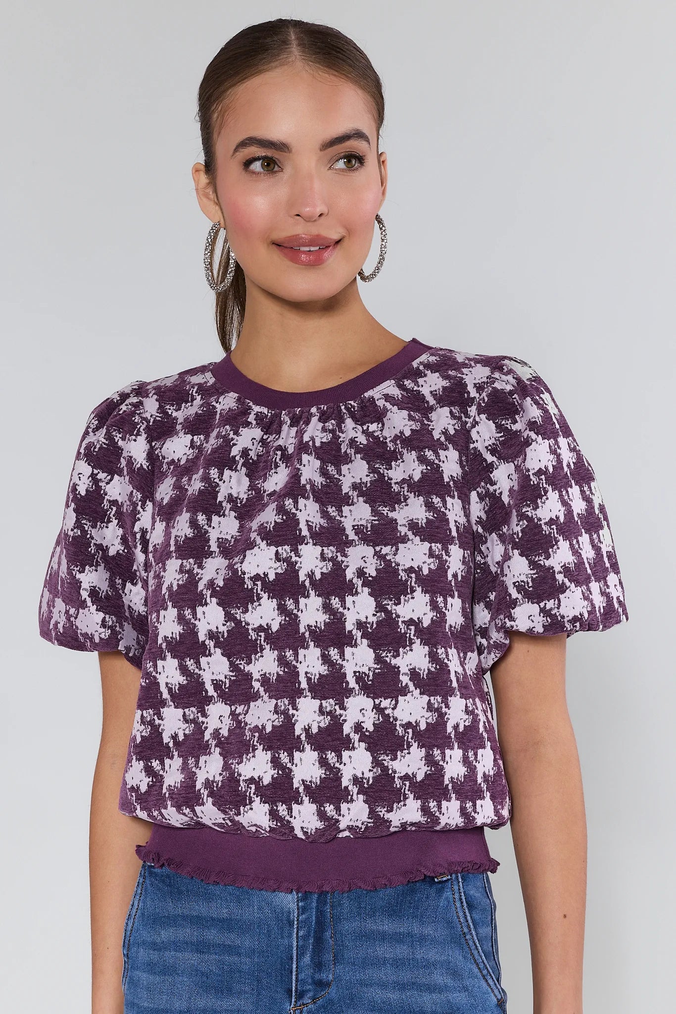 Woman wearing a purple Mason Top and white patterned top against a plain background