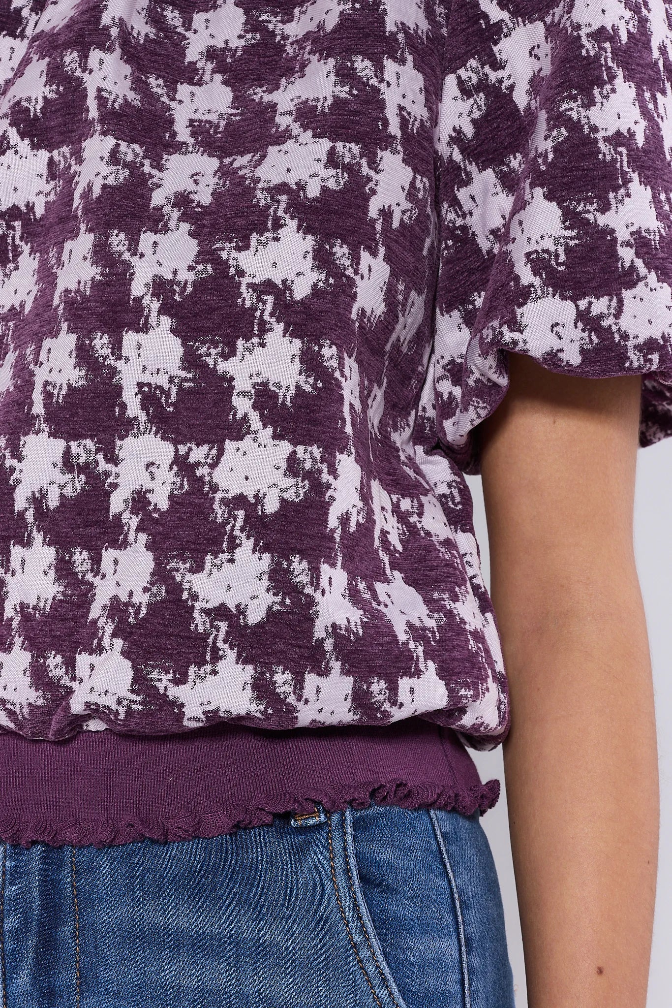 Woman wearing a purple Mason Top and white patterned top against a plain background