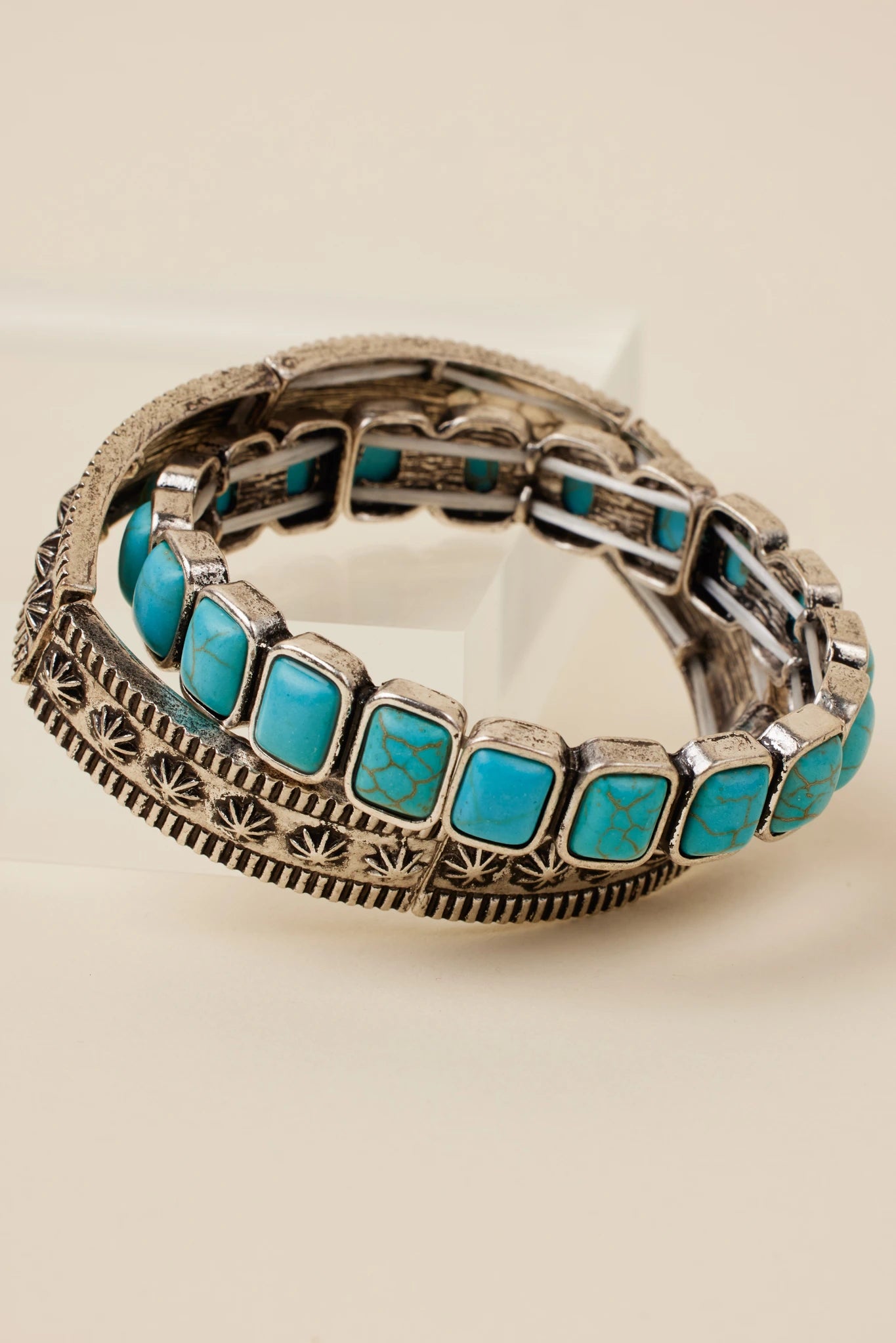 Bracelet with turquoise stones and silver band on beige background