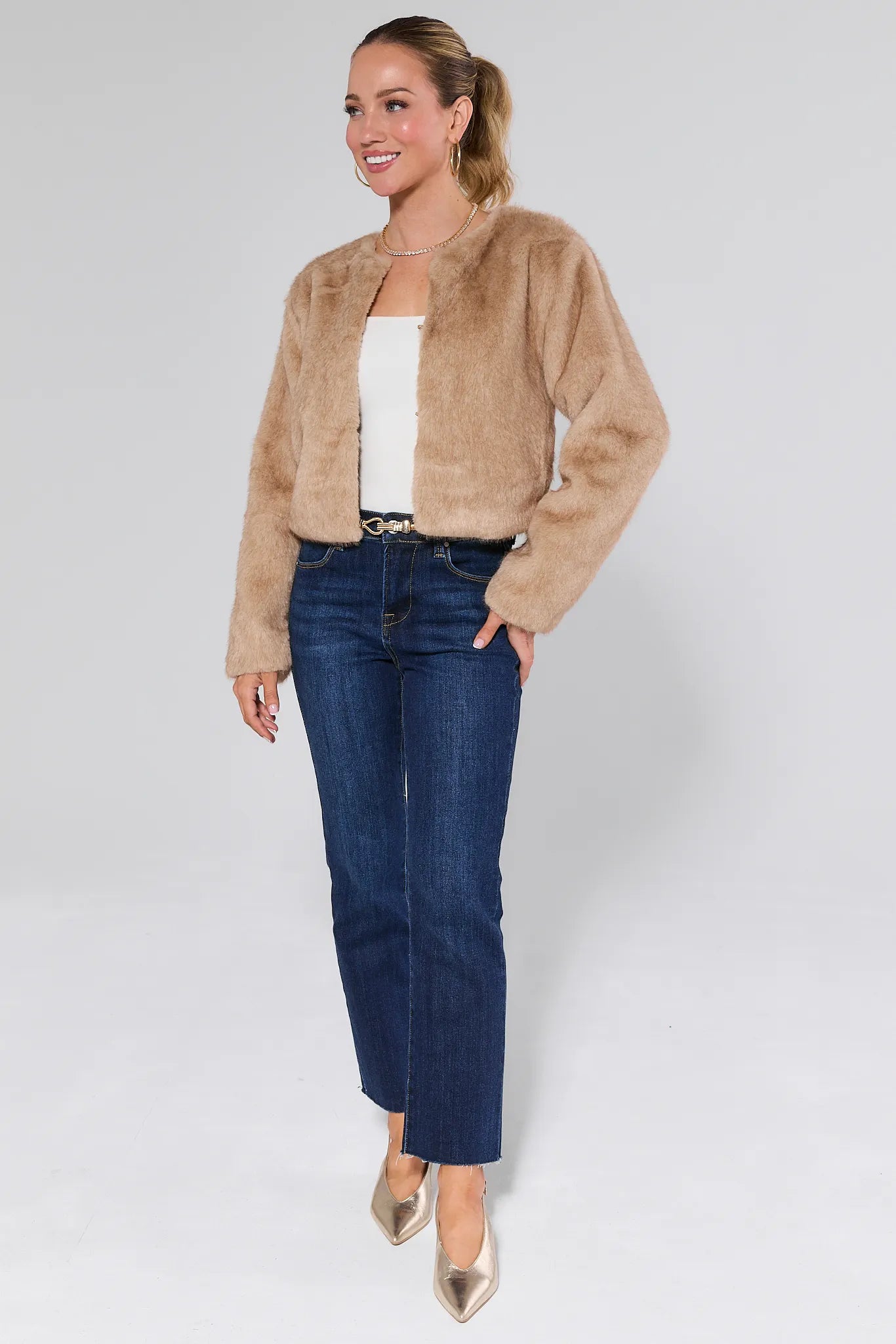 Woman wearing a Tamara Ivory Faux Fur Jacket and blue jeans on a white background