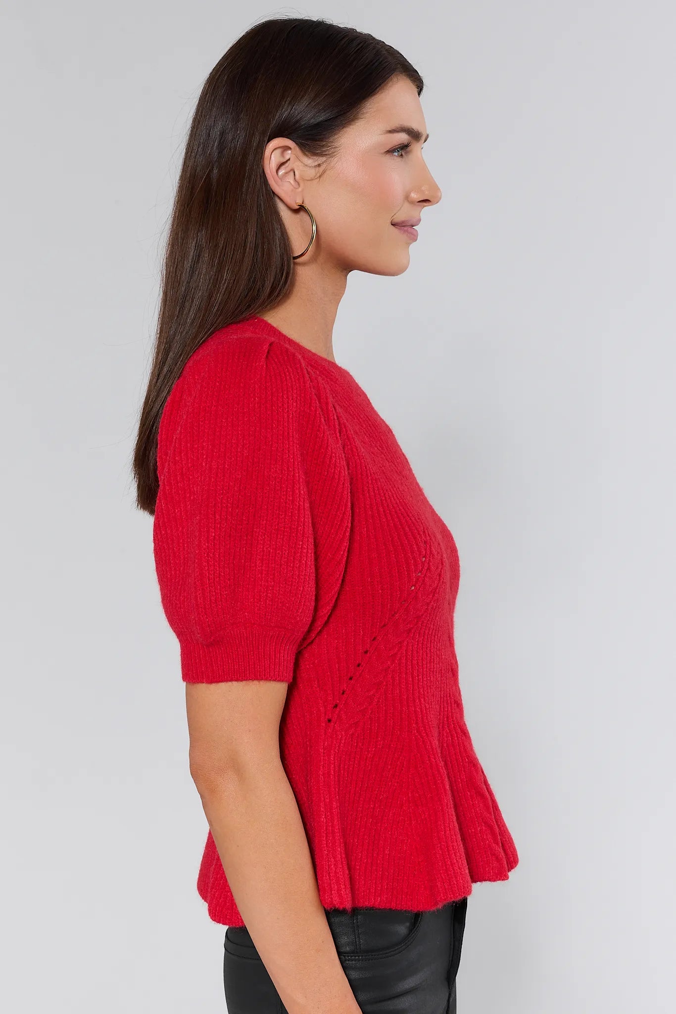 Woman wearing a red hillary sweater with puff sleeves against a plain background