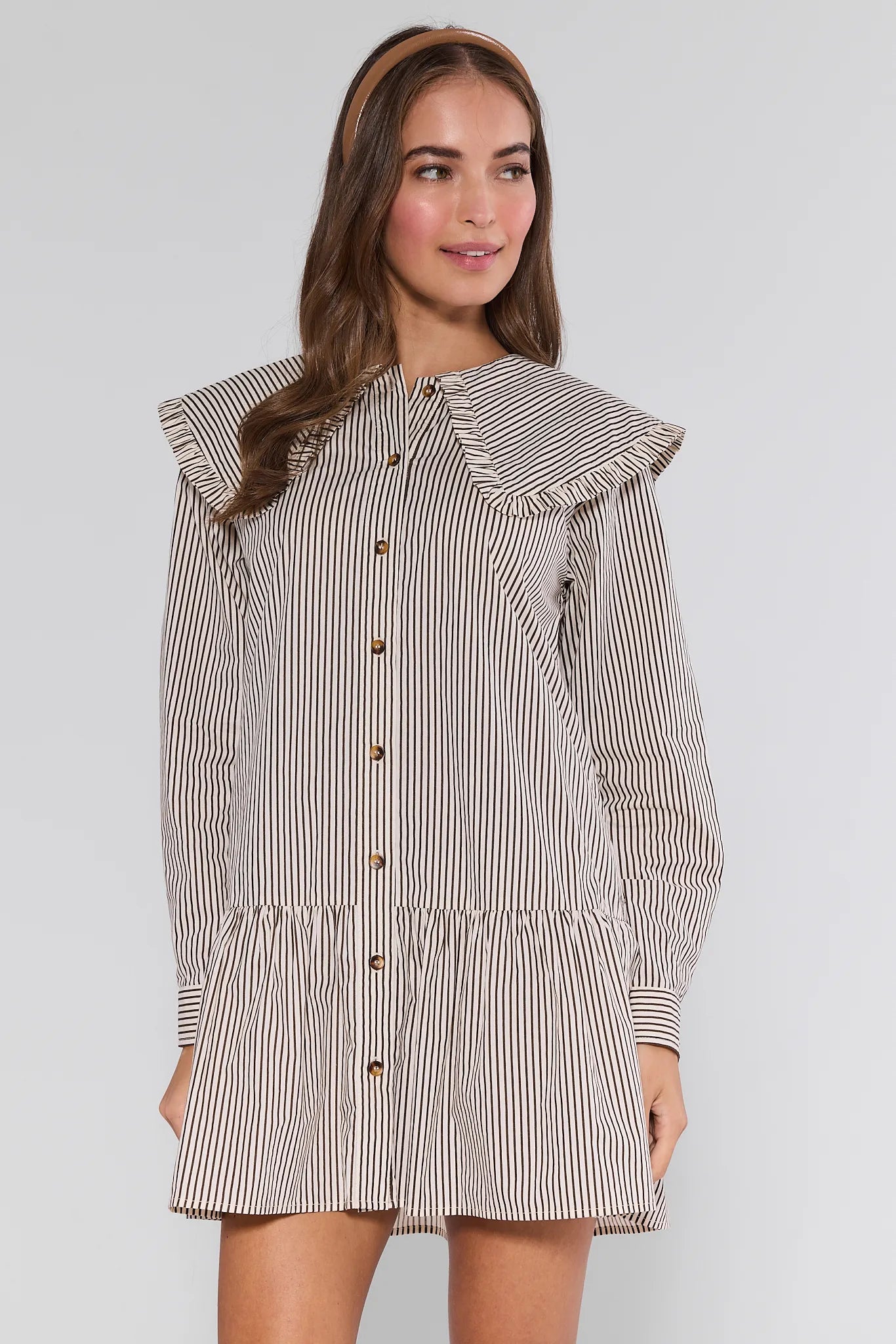 Woman wearing a striped Berkley Dress with ruffled shoulders on a white background