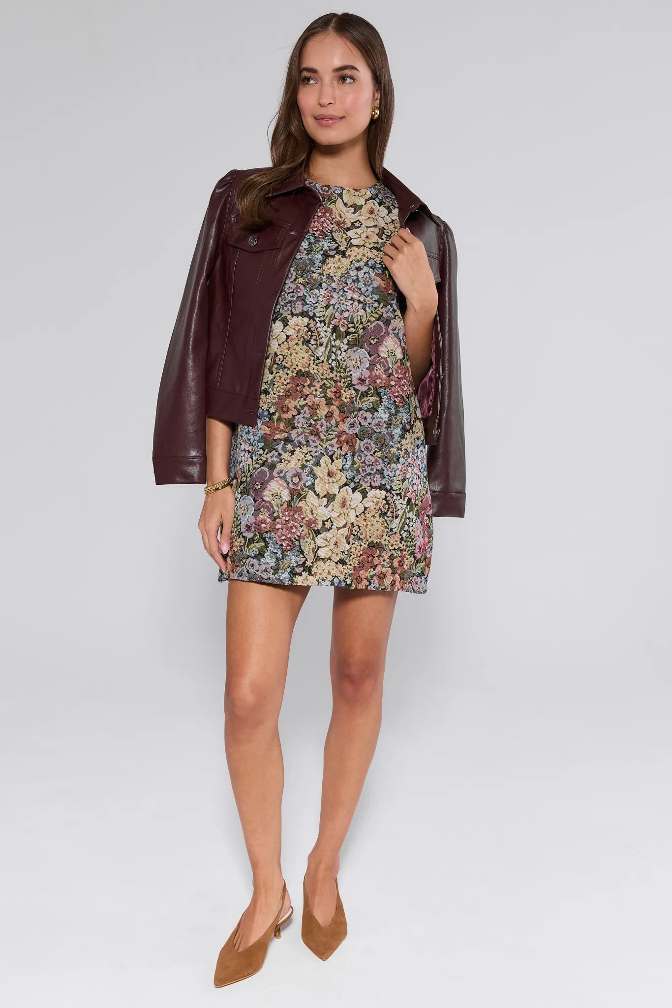 Woman wearing a floral Camdyn Dress with a brown leather jacket on a white background