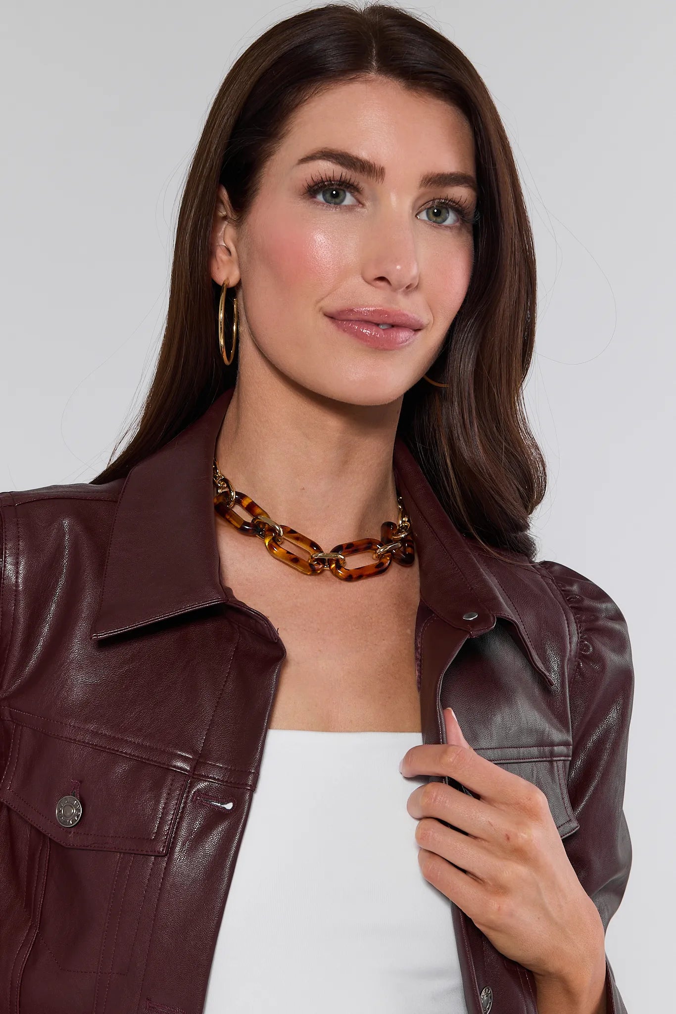 Woman wearing a brown leather jacket and tortoiseshell Cassie Necklace against a white background