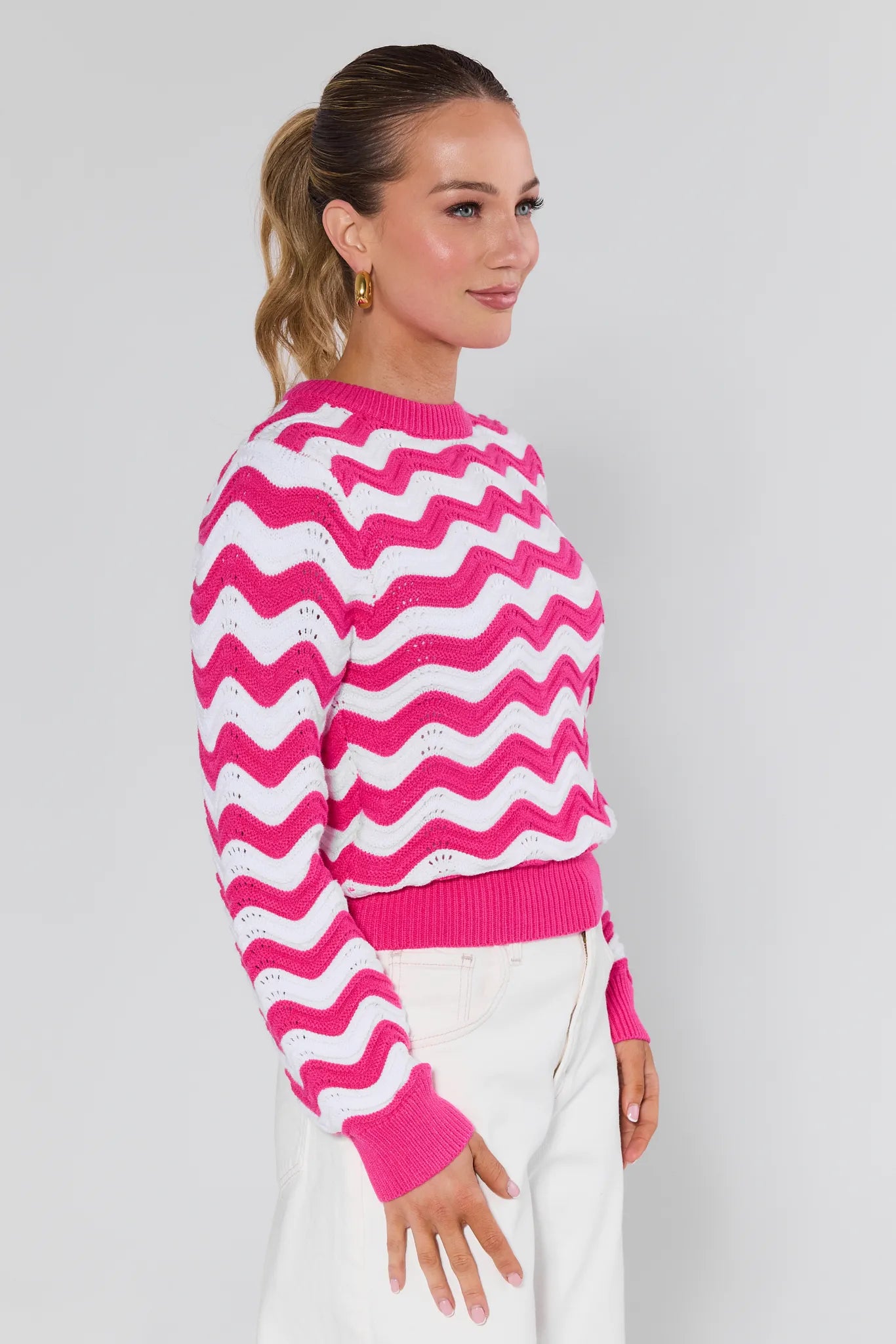 Woman wearing a Eliana Pink Chevron Knit Sweater against a plain background