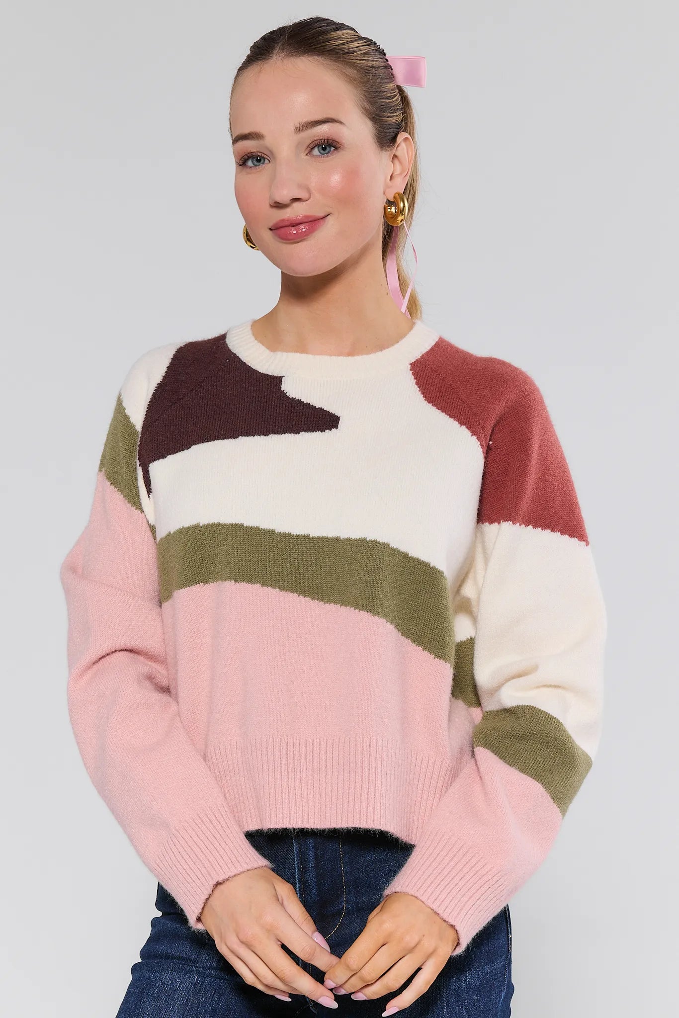 Woman wearing a colorful striped Beverly Sweater against a plain background
