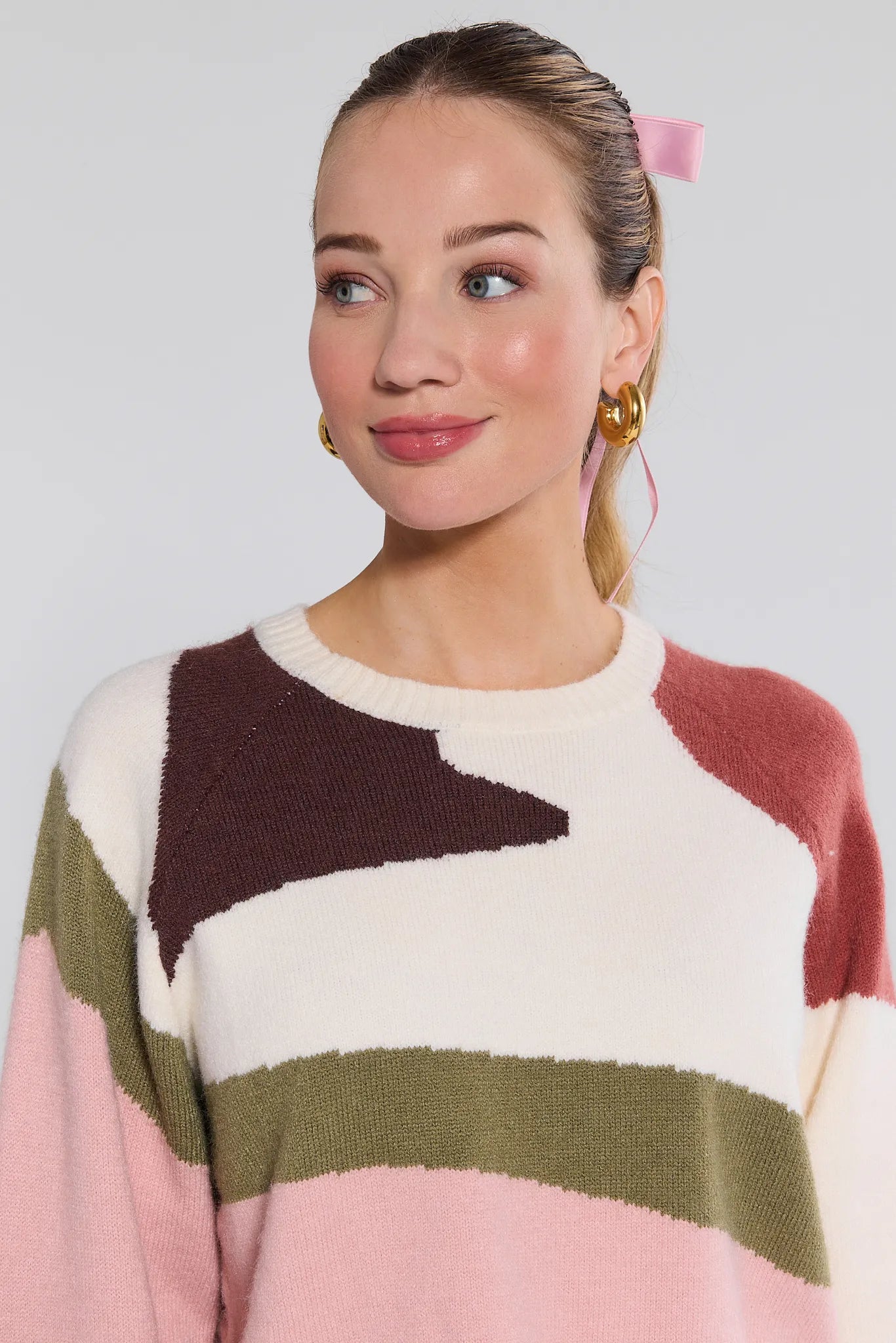 Woman wearing a colorful Beverly Sweater with a plain background