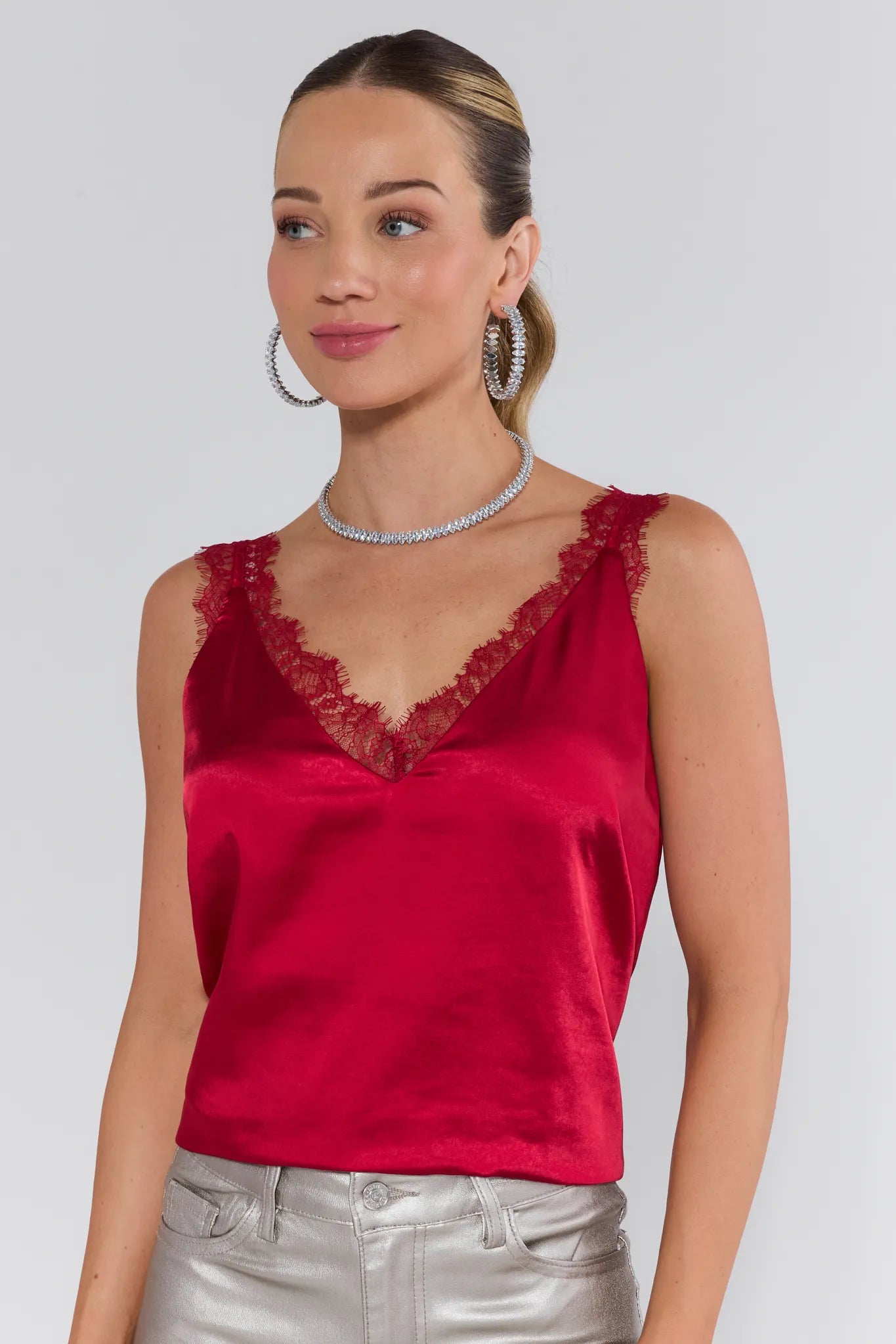 Woman wearing a red sleeveless top with lace details on a white background