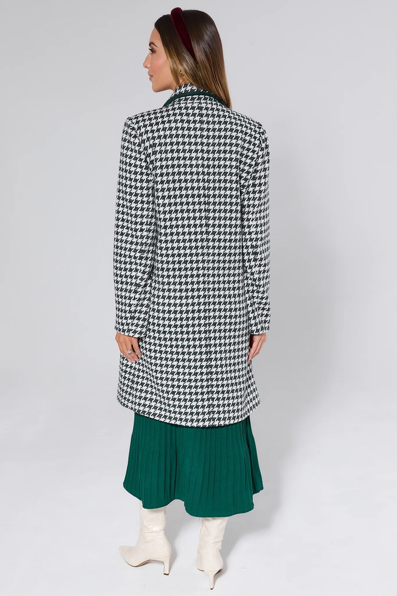 Woman wearing a Jonah Green Houndstooth Coat over a green dress with a plain background