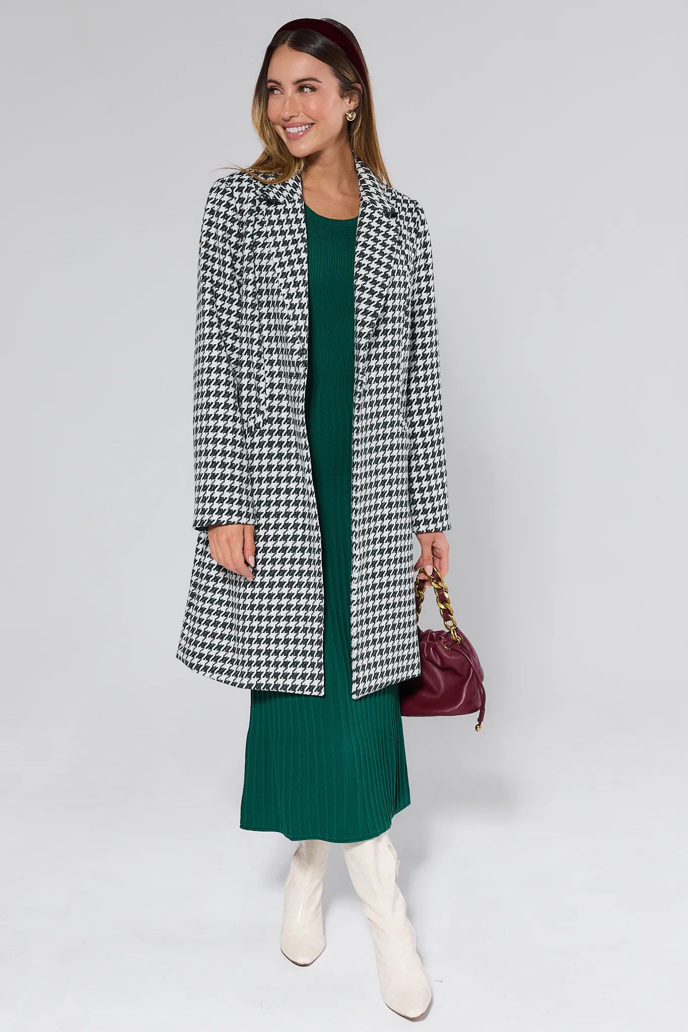 Woman wearing a Jonah Green Houndstooth Coat over a green dress with a plain background