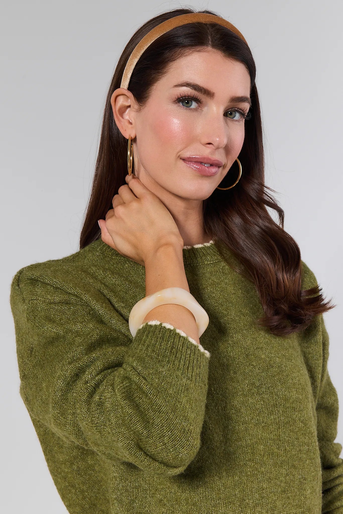 Woman wearing a green sweater with a plain background