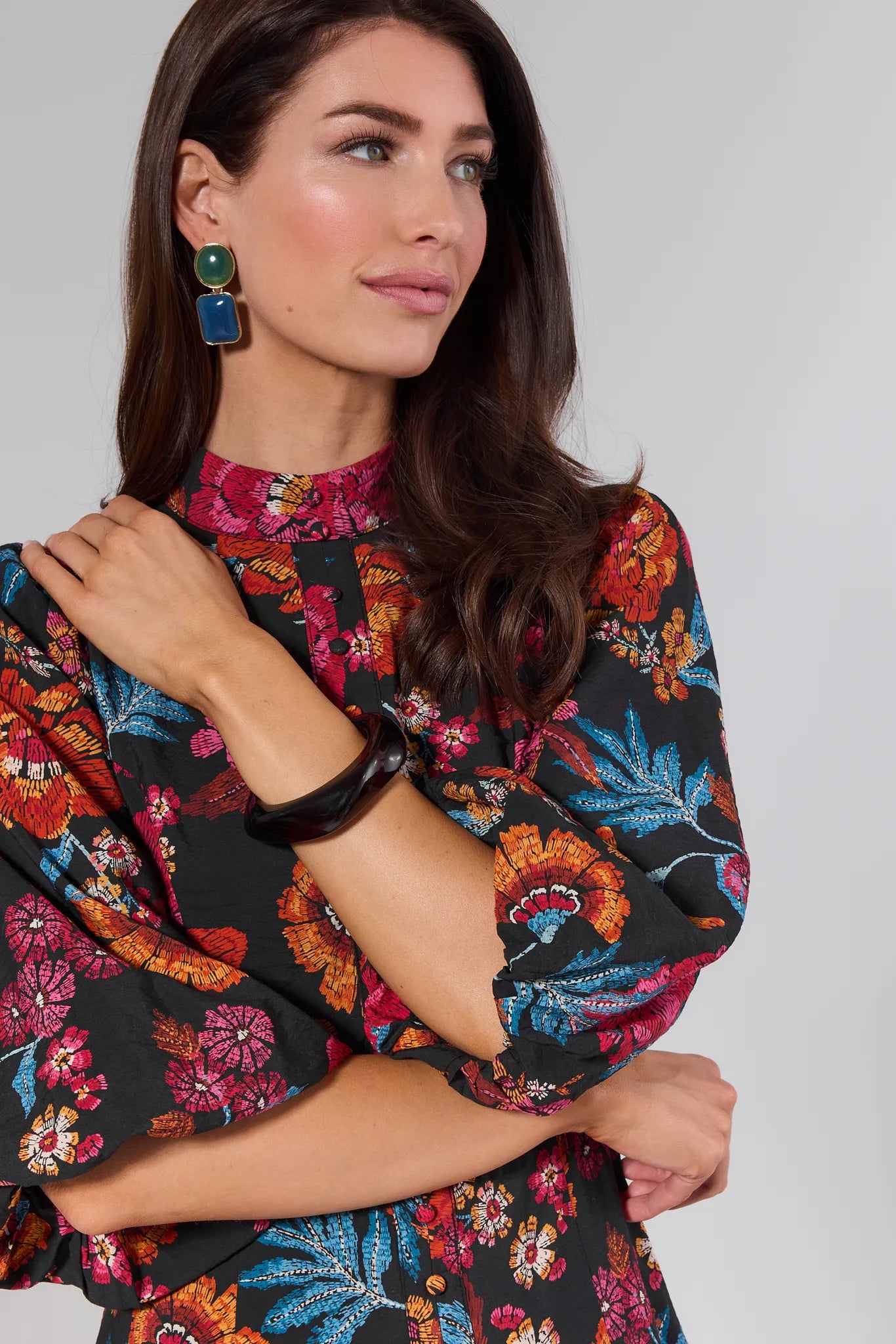 Woman wearing a colorful floral dress against a plain background
