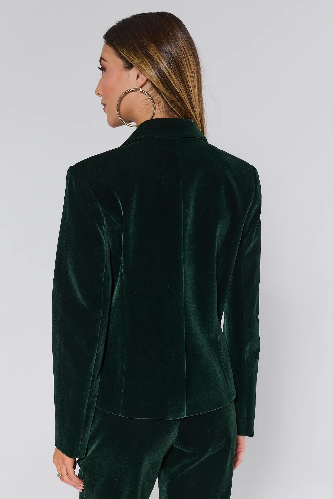Woman wearing a green velvet evie blazer and pants against a white background