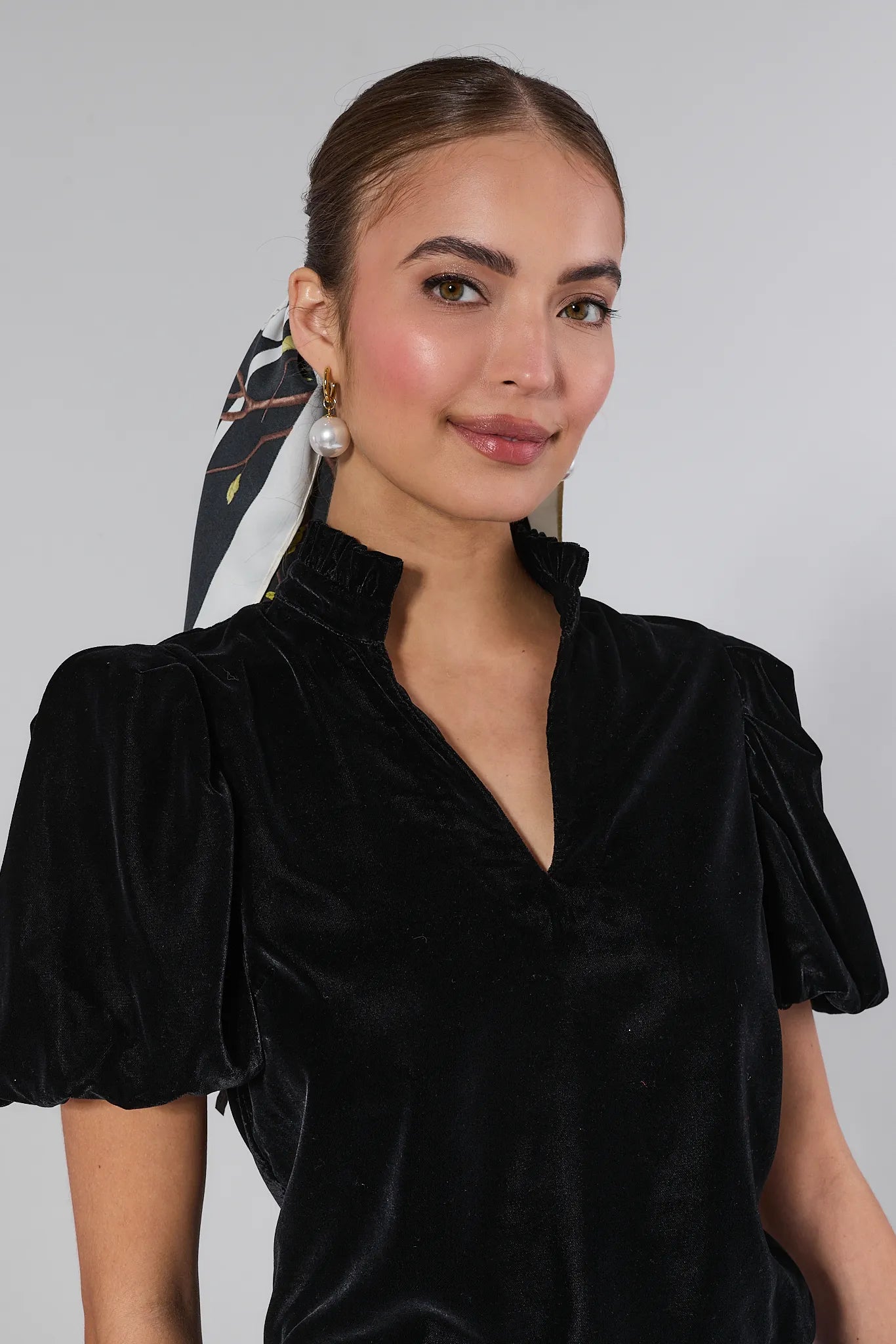 Woman wearing a Lynette Black Velvet Puff Sleeve Top against a plain background
