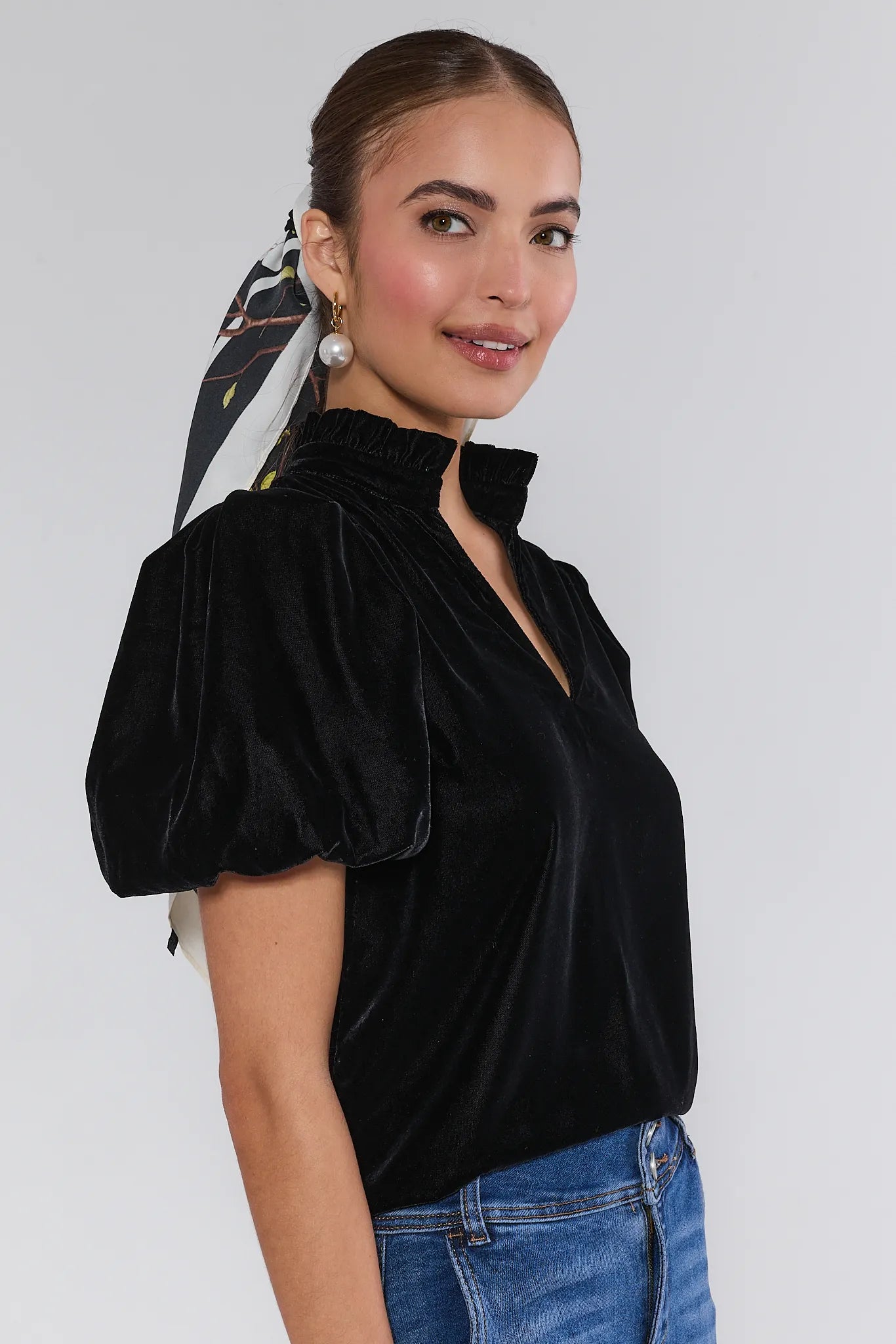 Woman wearing a Lynette Black Velvet Puff Sleeve Top against a plain background